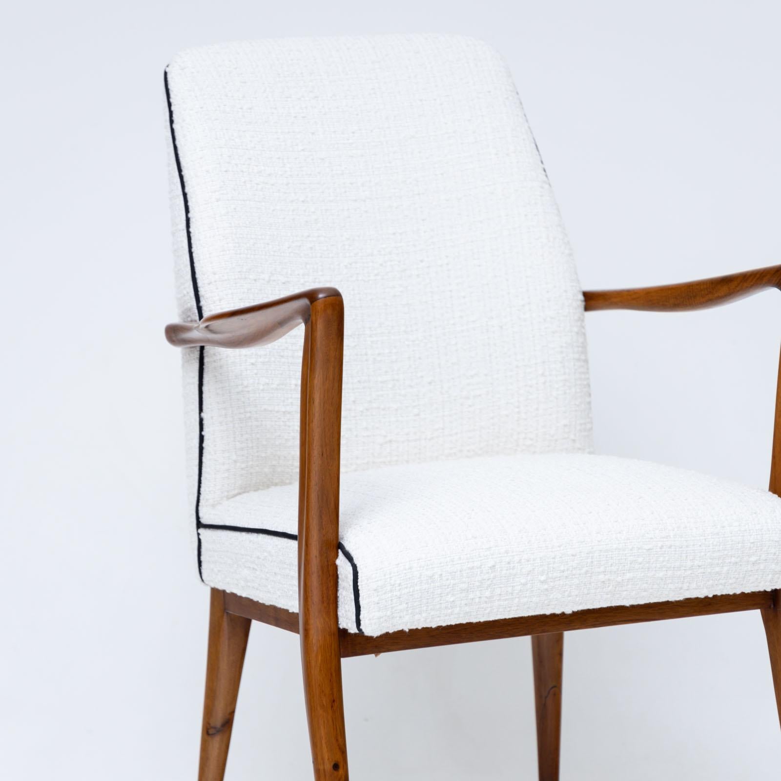 Set of six dining chairs featuring brass feet and sleek wooden frames with a polished finish. These chairs have undergone professional refurbishment and reupholstery. The high-quality white bouclé fabric is complemented by black piping, adding a