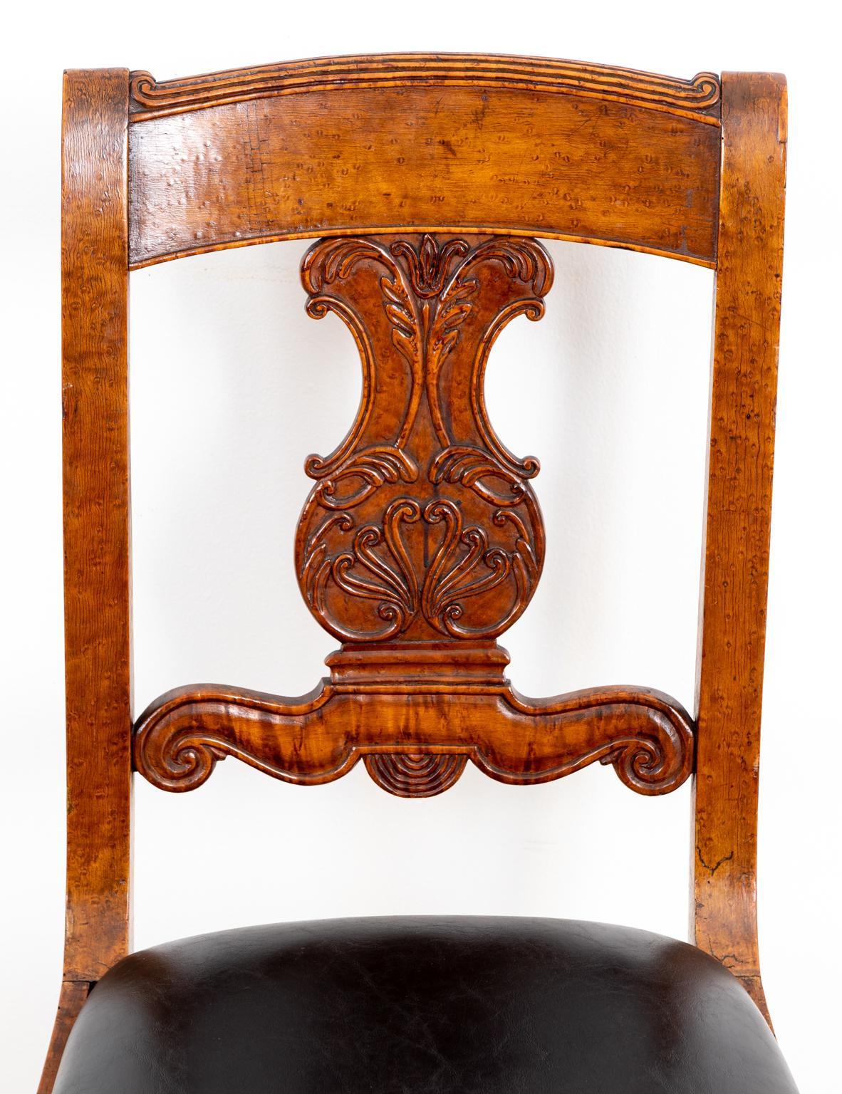 Set of six burled walnut dining chairs with leather upholstered slip seats, carved scrollwork and palmette back splats, and vase-and-ring turned legs, circa 1810. The chairs feature original patina. Please note of wear consistent with antique age