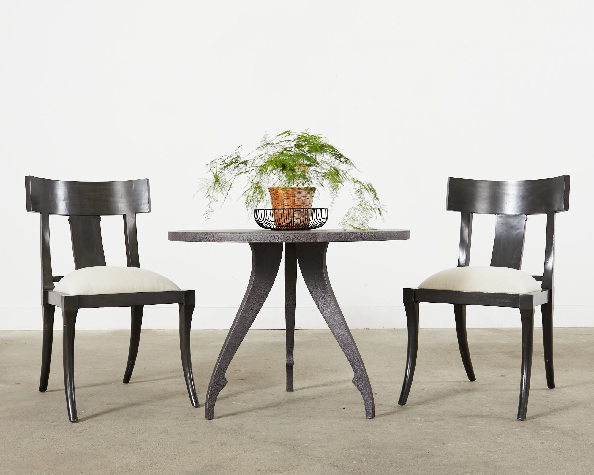 Dramatic set of six klismos dining chairs featuring a a hardwood frame with an ebonized lacquer finish in a dark grey tone. The frames have a classic tablet back and saber style legs in the Greco-Roman neoclassical style. The generous seat has a