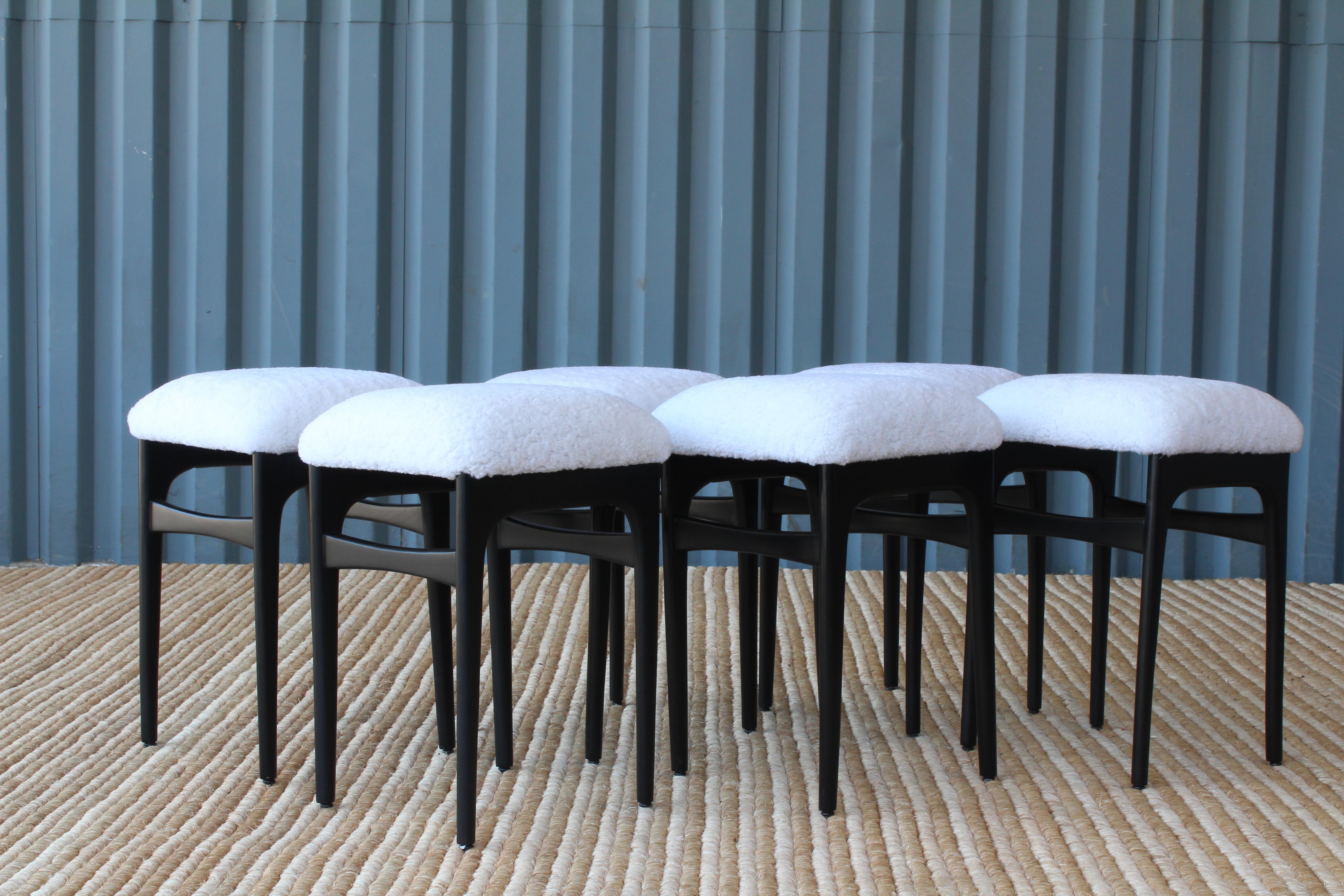 Pair of Danish teak stools in a black ebonized finish. They have all been reupholstered in plush white sheepskin. Sold as a pair