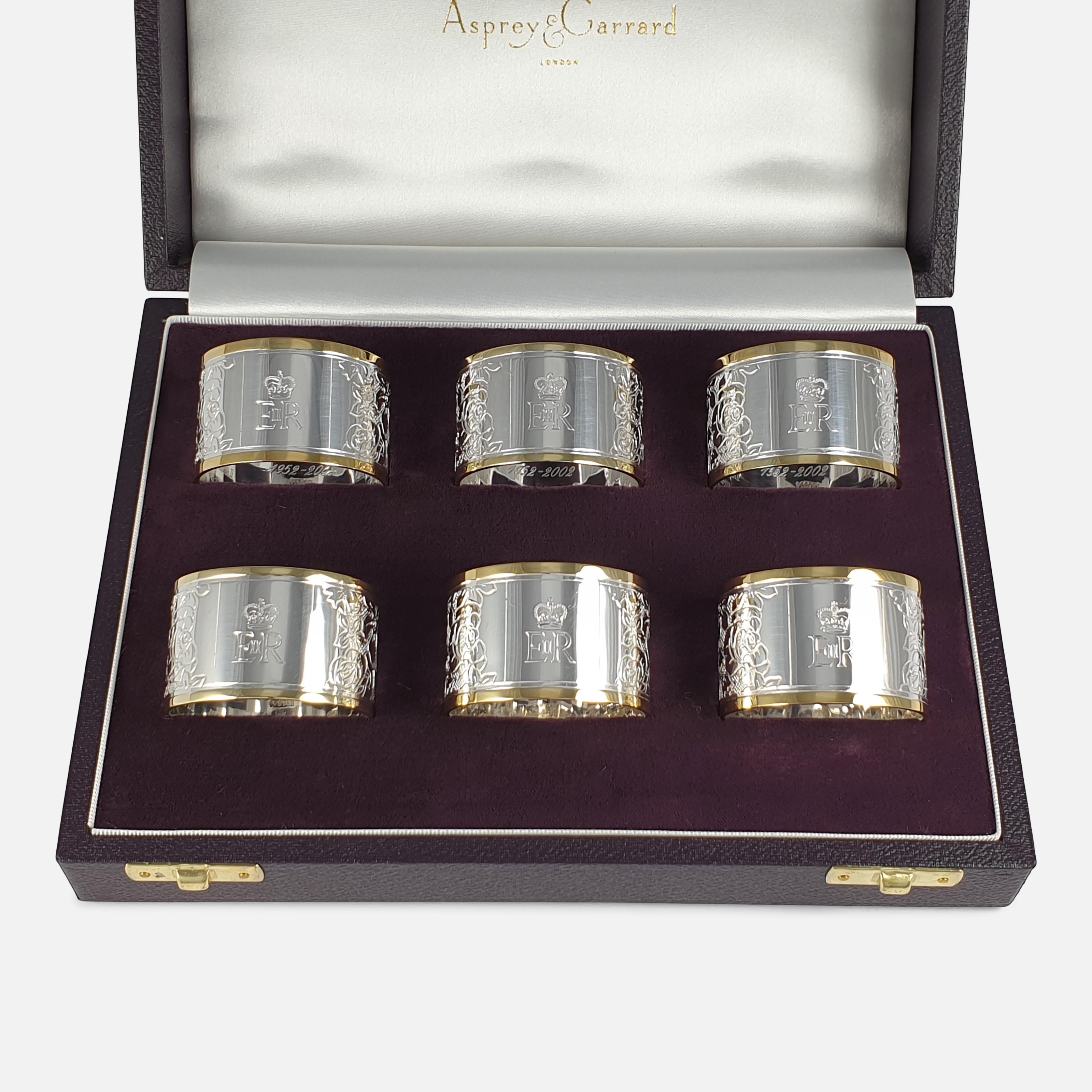 A cased set of six Elizabeth II parcel-gilt Britannia standard silver napkin rings, by Asprey & Co Ltd, London, 2002. The napkin rings are of typical round form, with a parcel-gilt rim; they are engraved with the Royal Cypher to the cartouche, and