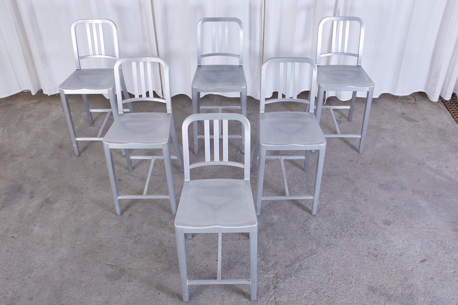 Iconic American set of six navy counter height stools finished in brushed aluminum made by Emeco. Designed in 1944 and still in production today. The navy chair is hand-formed from recycled aluminum. Seat is stamped Emeco on back with a