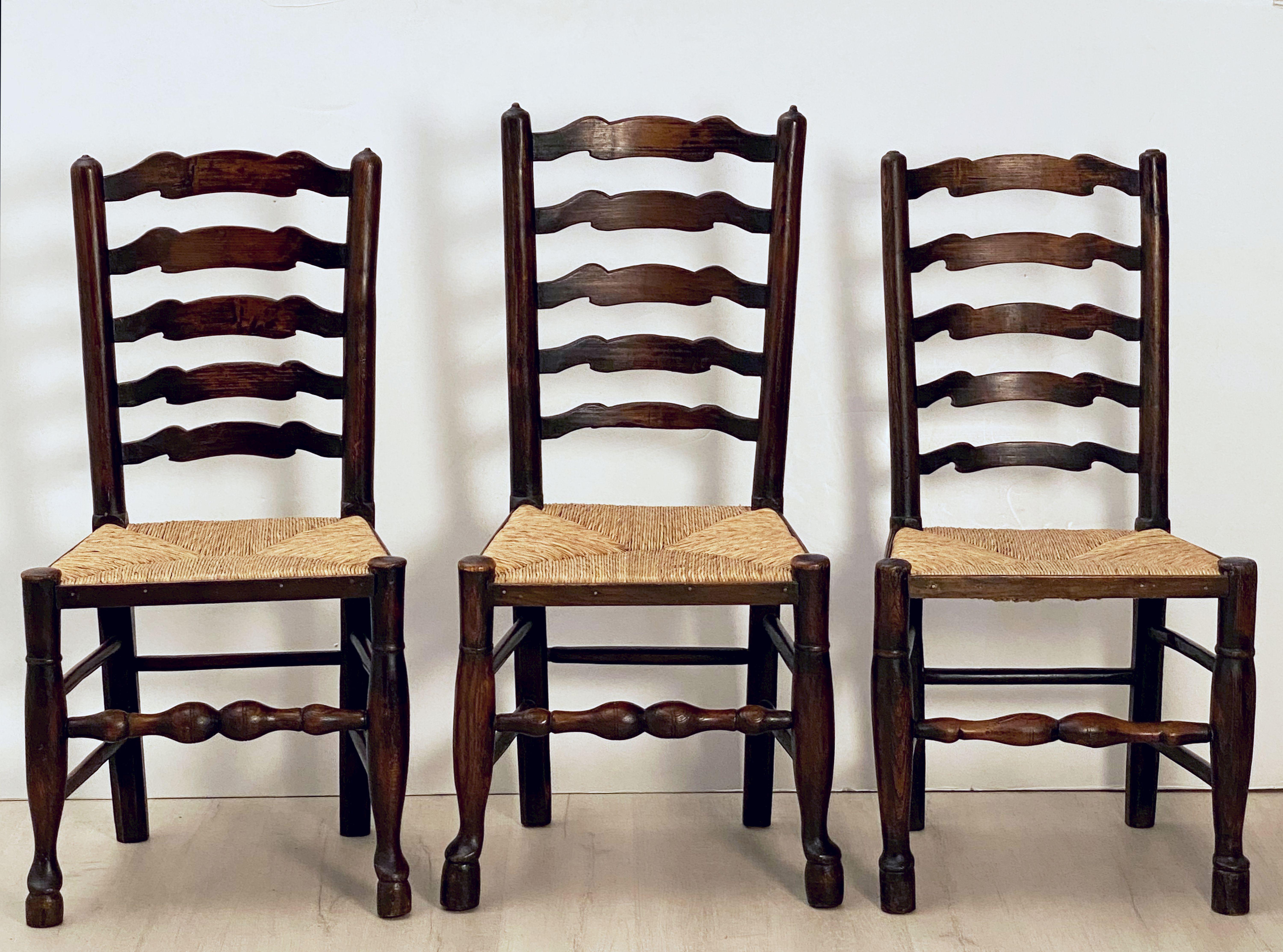 A fine set of six English ladder-back chairs with handsome woven rush seats.
Featuring nicely-turned slats on the backs and turned legs and supports, slight variation from chair to chair.

A Classic rustic English country or farm or cottage home