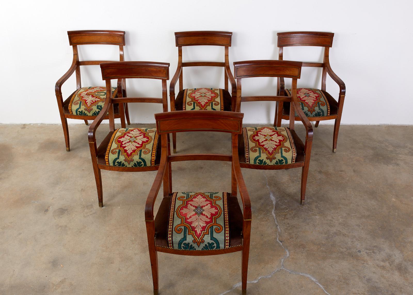 Distinctive 19th century set of six English Regency bronze mounted walnut dining armchairs or library armchairs. The chairs feature an Arts & Crafts era needlepoint decorated seat with brown velvet borders and brass tack nailhead trim. Substantial