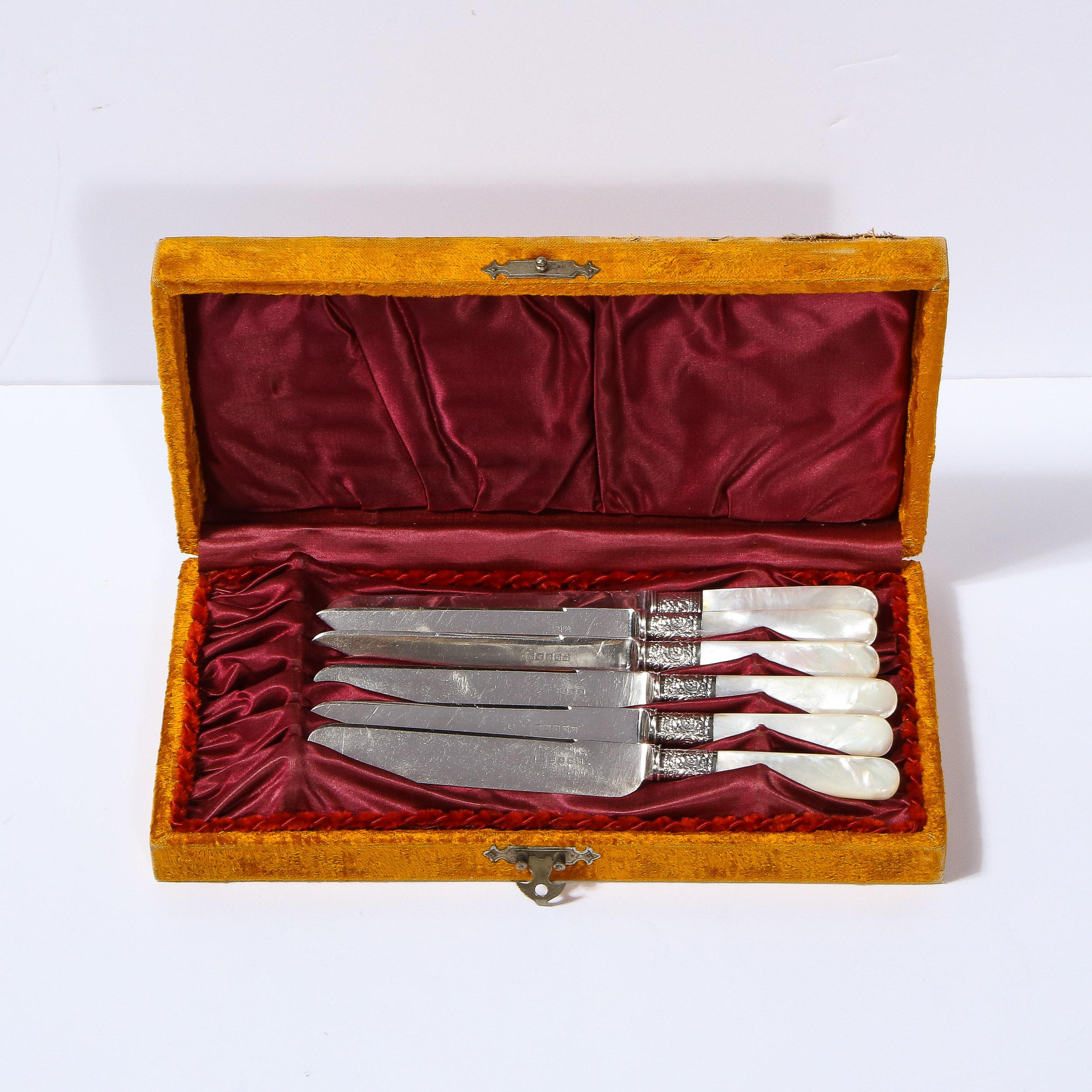 This stunning set of six Victorian knives were realized in England during the 19th Century. They feature mother of pearl handles with neoclassical stylized floral detailing in Sheffield silver on the shoulders and rectangular curved blades with