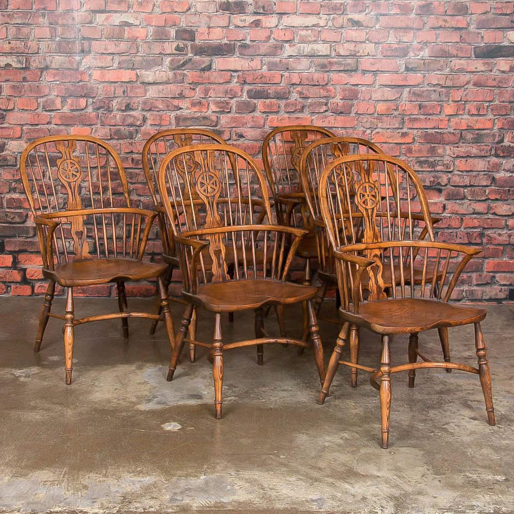 The visual draw of this exceptional set of six elm Windsor armchairs is in the Classic styling, featuring pierced splat backs and saddle-style seats that make these chairs extremely comfortable. Crafted in the traditional style with upper spindles