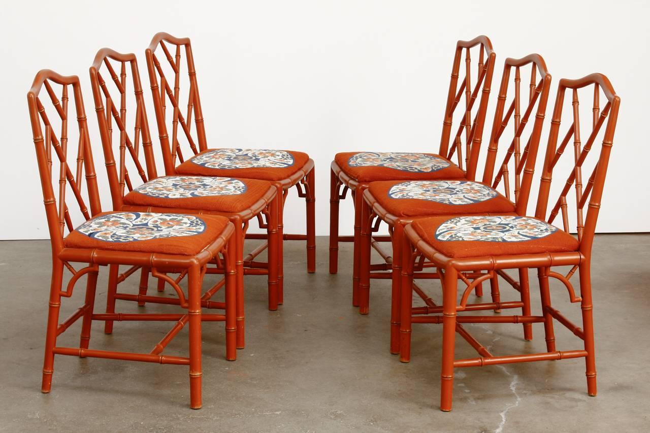 Colorful set of six faux bamboo dining chairs made in the Chinese Chippendale taste. Featuring a Hermes orange style lacquered finish with needlepoint seats. The frames have a carved faux bamboo decoration with an open fretwork geometric back.