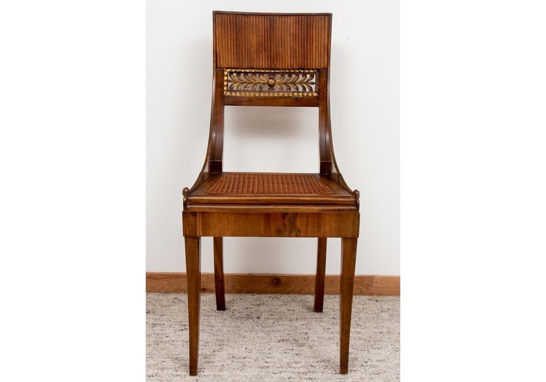 Notable Italian made set of chairs with classic Klismos form in walnut with gilt inlay carved inset back panels and hand-caned seats. The attention to detail in the construction is very fine, particularly noticeable in the delicately fluted carving