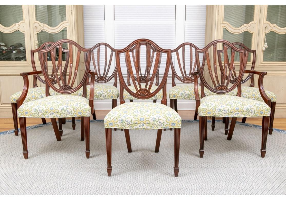 With two arm and six side chairs. The classic Sheraton style backs with reeded frames and splats ending in half rosettes. Raised on square tapering reeded front legs and square splayed back legs. The shaped seats upholstered in a yellow and blue on