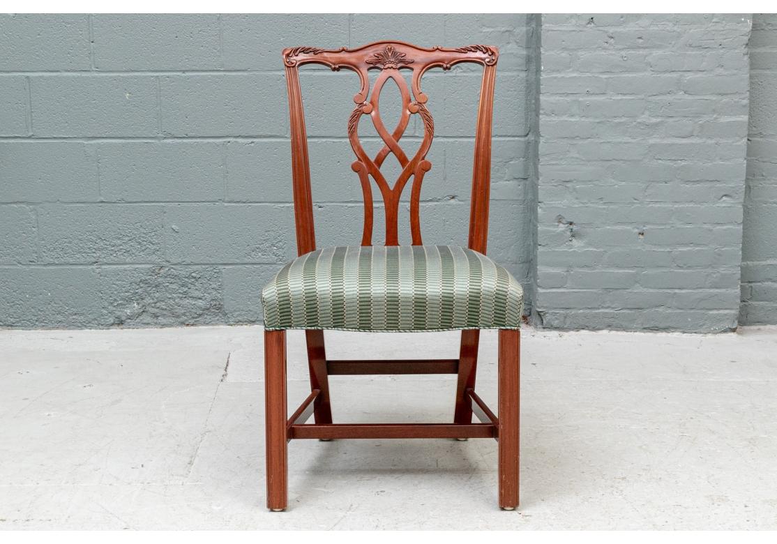 With Classic curved crest rails with carved leaves and center palmette, and openwork interlaced splats with leafy details. Raised on square front legs and square splayed back legs, with H and back stretchers. The seats upholstered in a green on