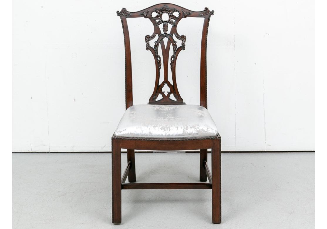Classic Chippendale style carved dining chairs with wild Space Age type distressed seat fabric in silvered material. With two arm and four side chairs. With curved crest rails and openwork carved leafy round motifs on top of the carved splats with