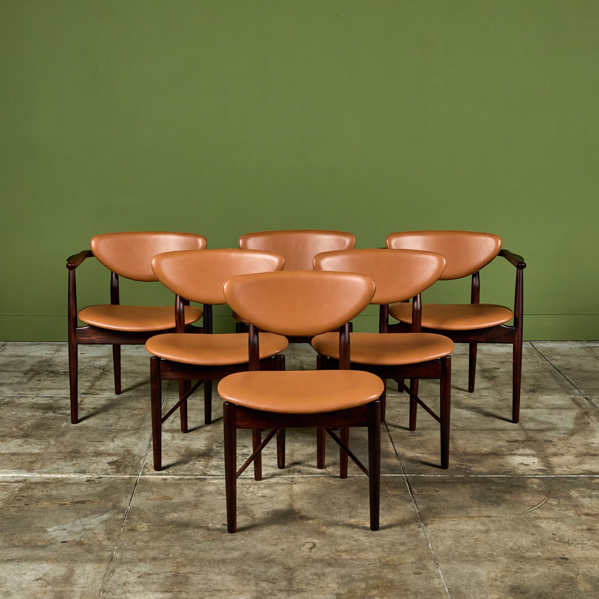 Designed in 1953 by Finn Juhl for Niels Vodder, Denmark, the Model 109 and 59 dining chairs are a rare design. This rosewood set featuring two armchairs and four side chairs has been fully restored and showcases new tan leather