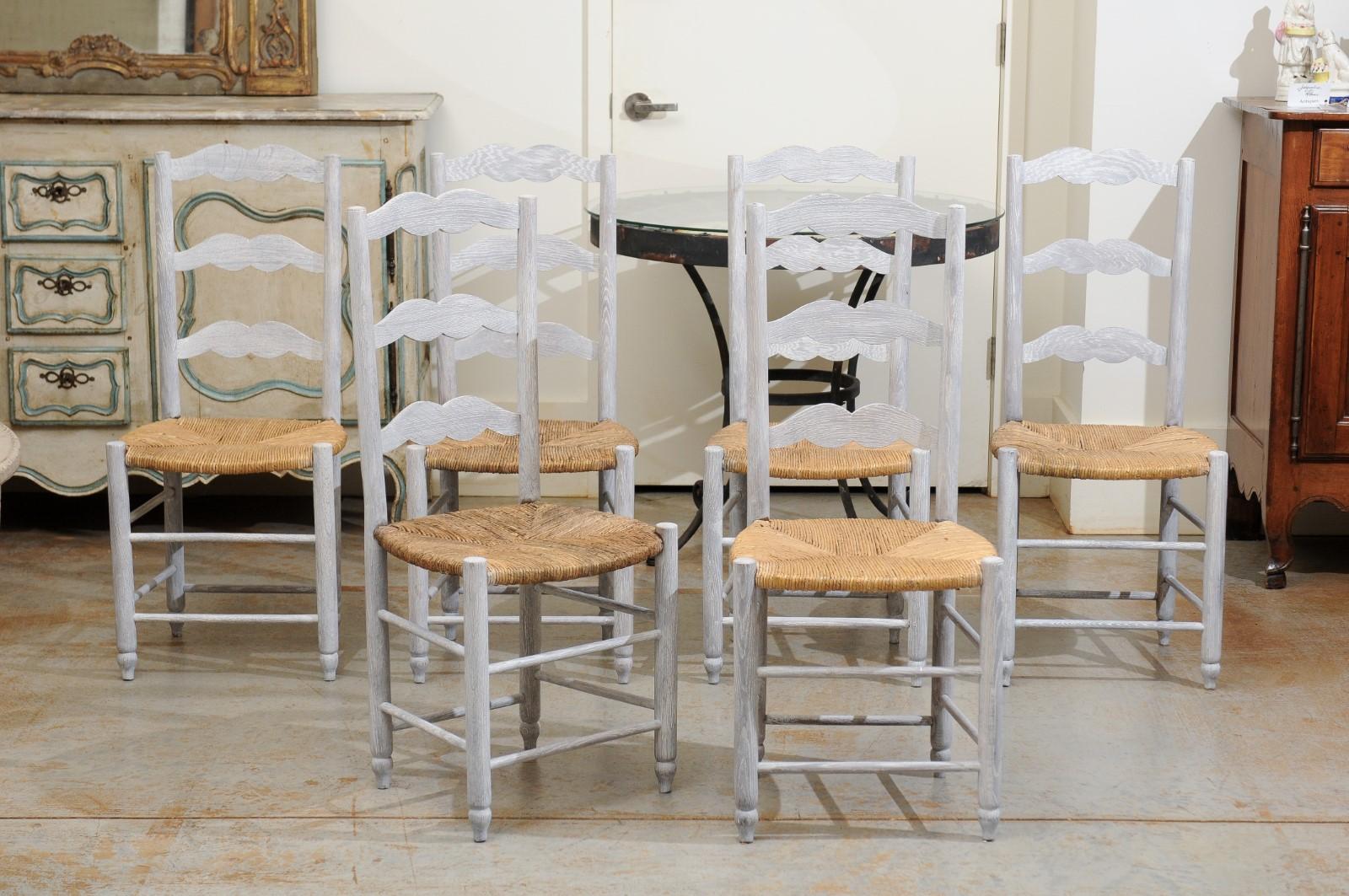 A set of six French bleached oak ladder back dining room side chairs from the 19th century, with rush seat and cylindrical legs. Born in France during the politically dynamic 19th century, each of this charming set of six dining chairs features a