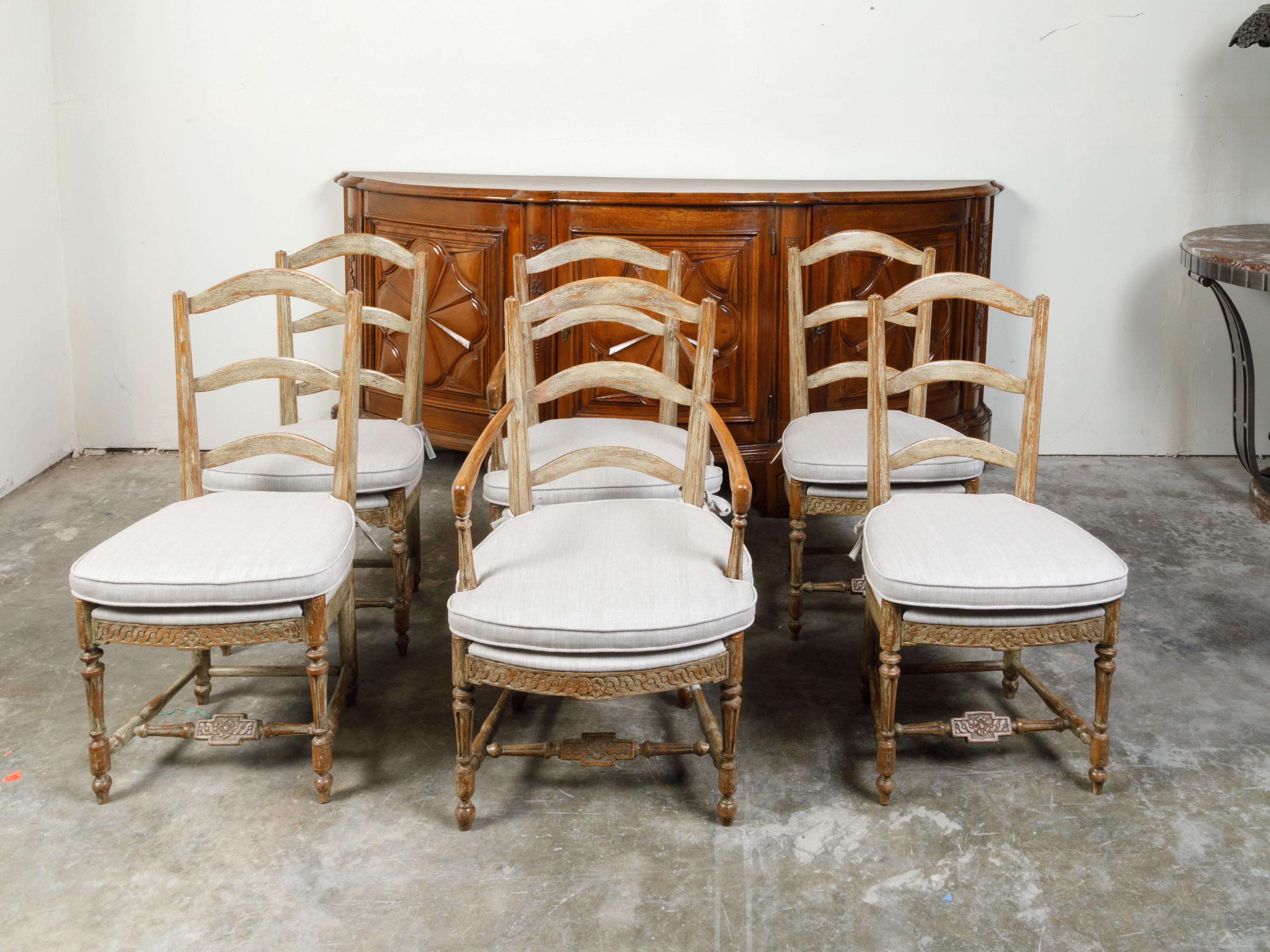 A set of six French wooden dining room chairs from the 19th century, with four sides, two arms, carved guilloche motifs and custom cushions. Created in France during the 19th century, each of this set of dining chairs features a curving ladder back