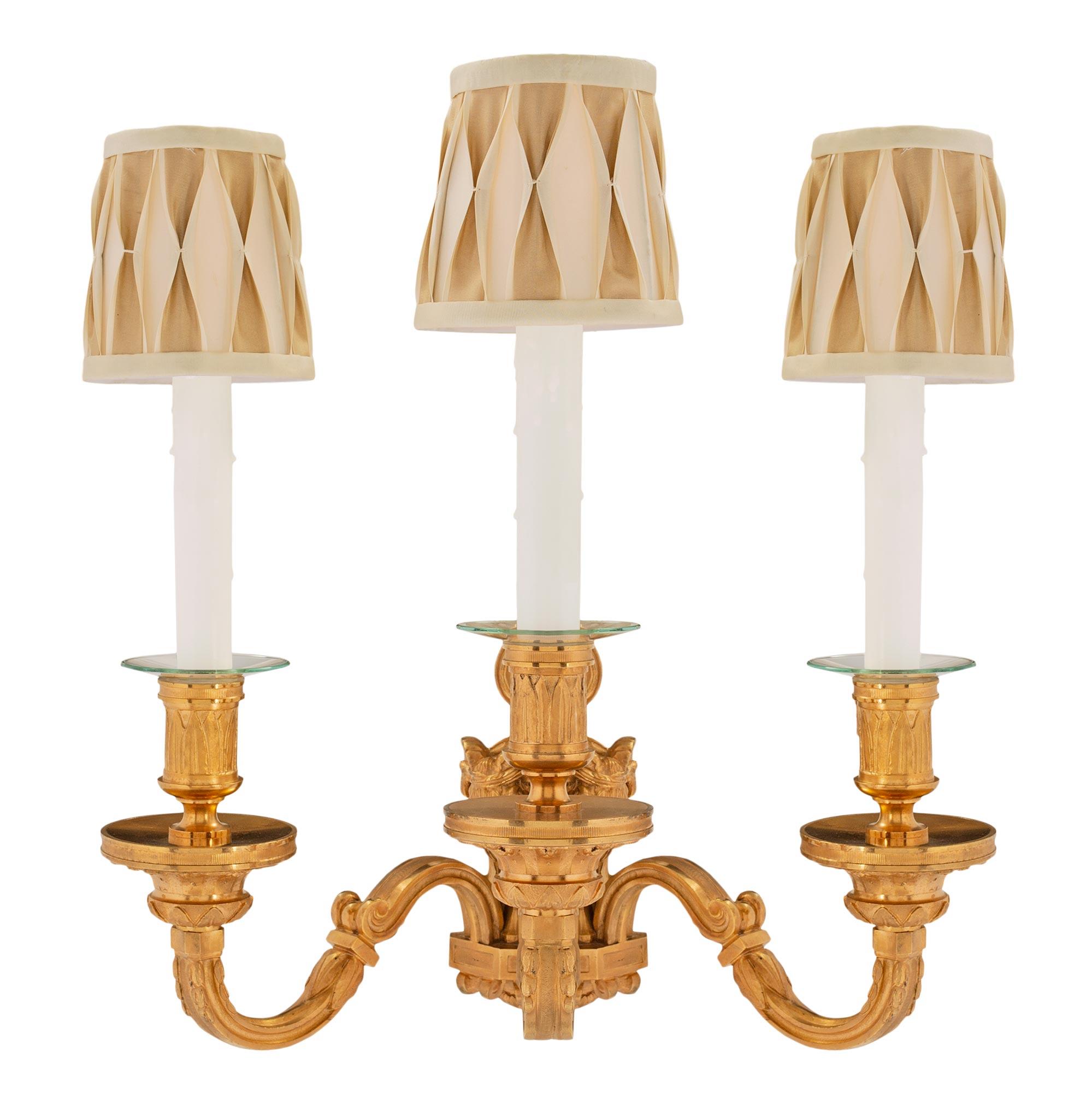 A rare set of six stunning French 19th century Louis XVI style ormolu sconces. Each three arm sconce has a handsome backplate with ram heads and ring, inverted finial and cut corner base. The three S-scrolled arms are decorated with acanthus leaves