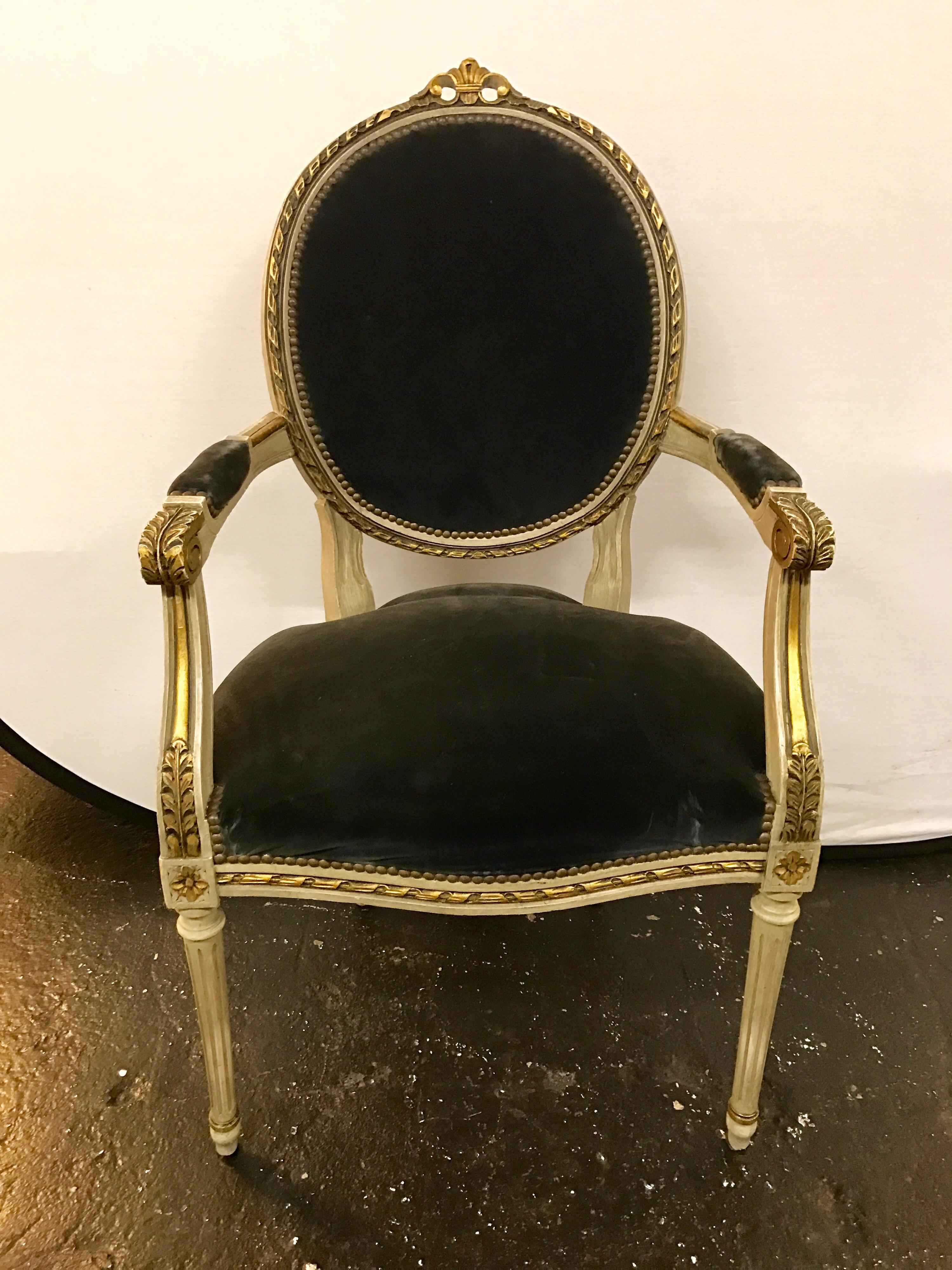 Antique cream painted French Louis XVI dining chairs with carved giltwood detail and charcoal velvet upholstery. There is one arm chair and five side chairs.