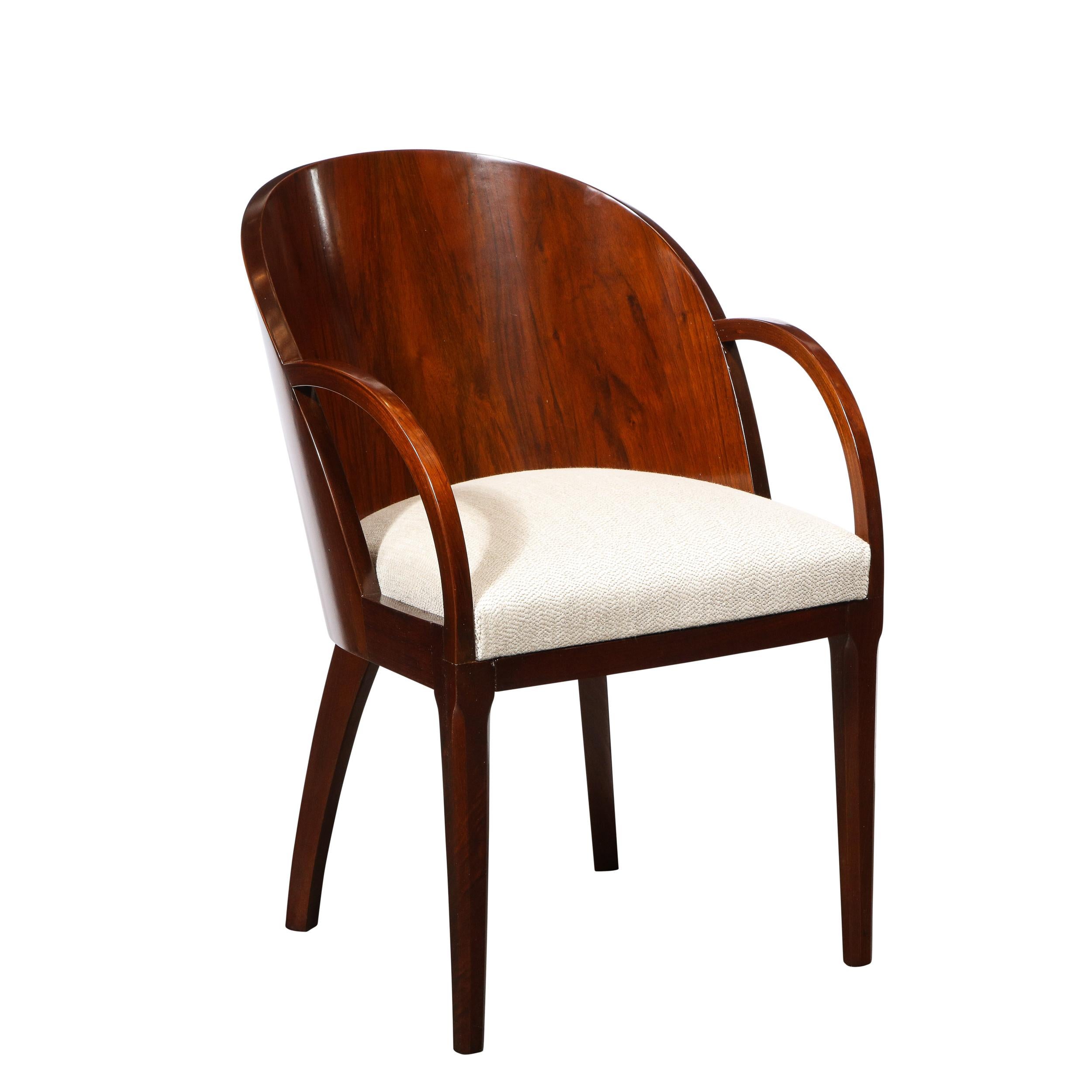 This sophisticated set of six Art Deco dining chairs were realized in France circa 1930. They feature gently rounded barrel backs; stylized klismos legs; streamlined arms; and upholstered seats in an oyster hued cotton fabric with a subtle linear