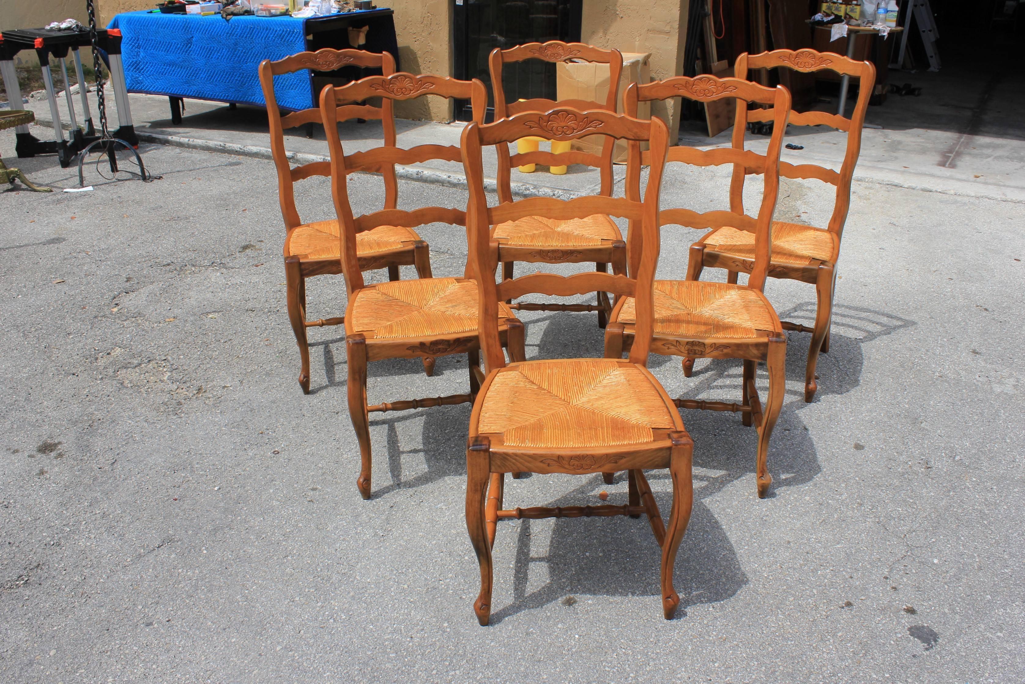 Set of six provincial ladder back chairs, circa 1910s. Solid walnut. Original rush seats. Crest rail with a central carved shell. Cabriole legs ending in scrolled French toes on pegs. Slip seats for easy cleaning. Size: 16 D, 17 W, 39.50 H (seat H