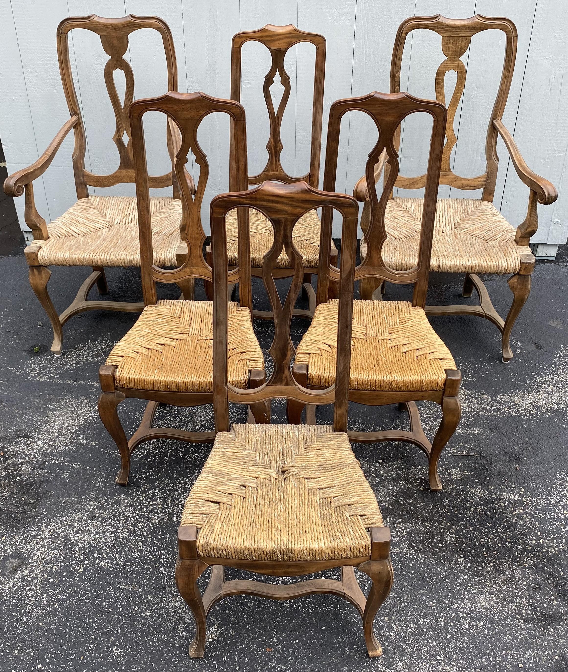 A fine set of six hand carved French country walnut dining chairs, two arm chairs and four side chairs, each with a simple carved crest, pierce carved splat, cabriole legs, and H form stretchers. The rush seats on the side chairs are slip seats, a
