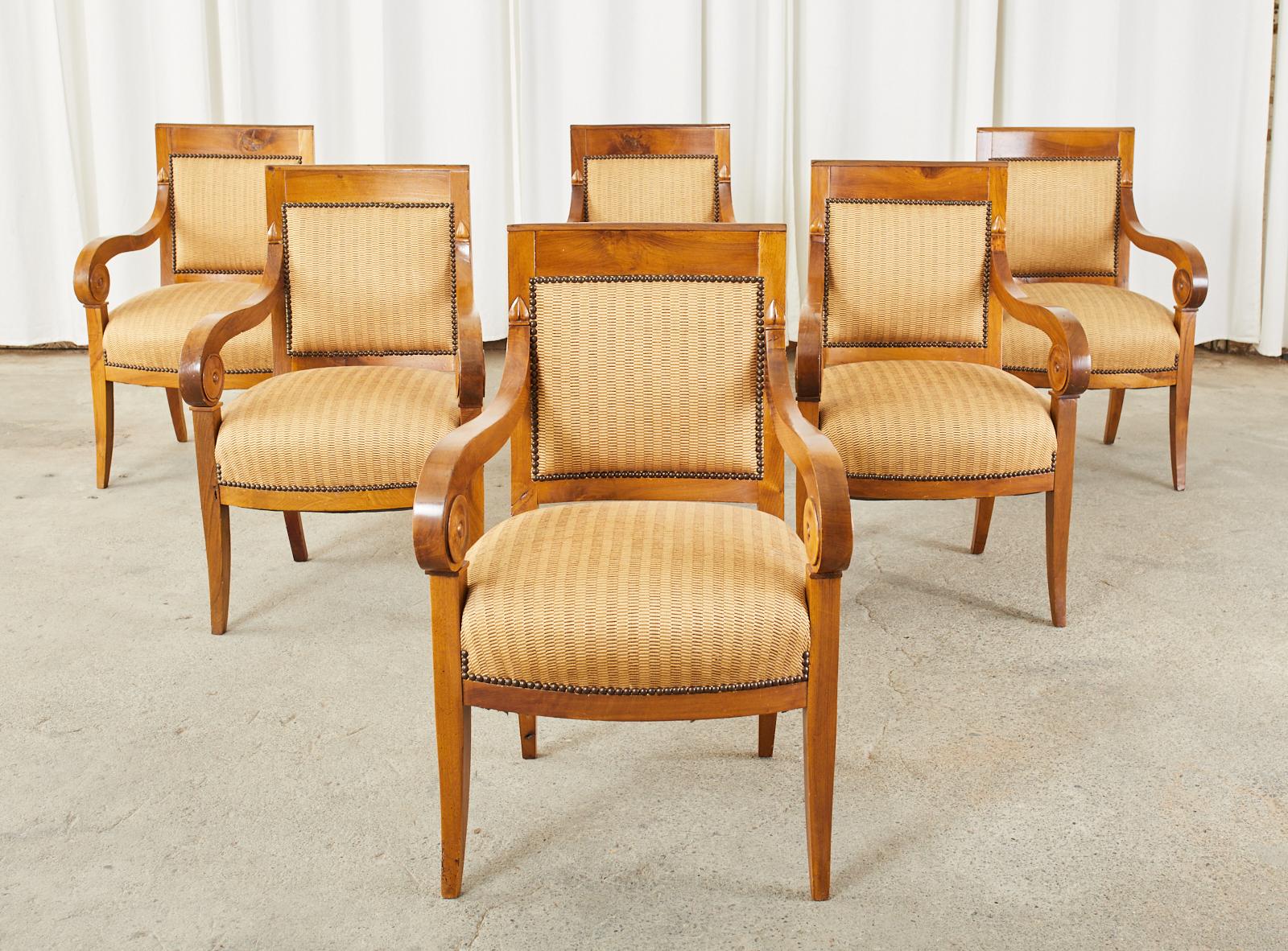 Remarkable 19th century set of French walnut dining chairs or armchairs crafted in the Empire or Biedermeier taste. The chairs feature thick walnut frames that showcase the dramatic grain patterns of the wood with a beautifully aged patina. The