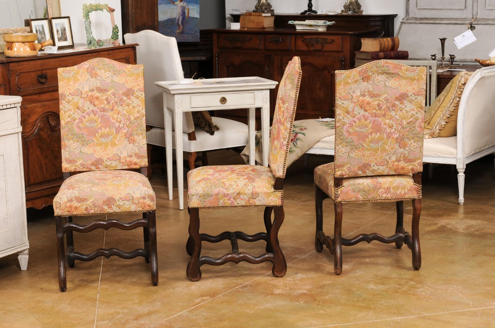 A set of six French Louis XIII style dining room side chairs from the 19th century, with os de mouton bases, slanted camelbacks, cross stretchers and used floral upholstery. Created in France during the 19th century, each of this set of side chairs