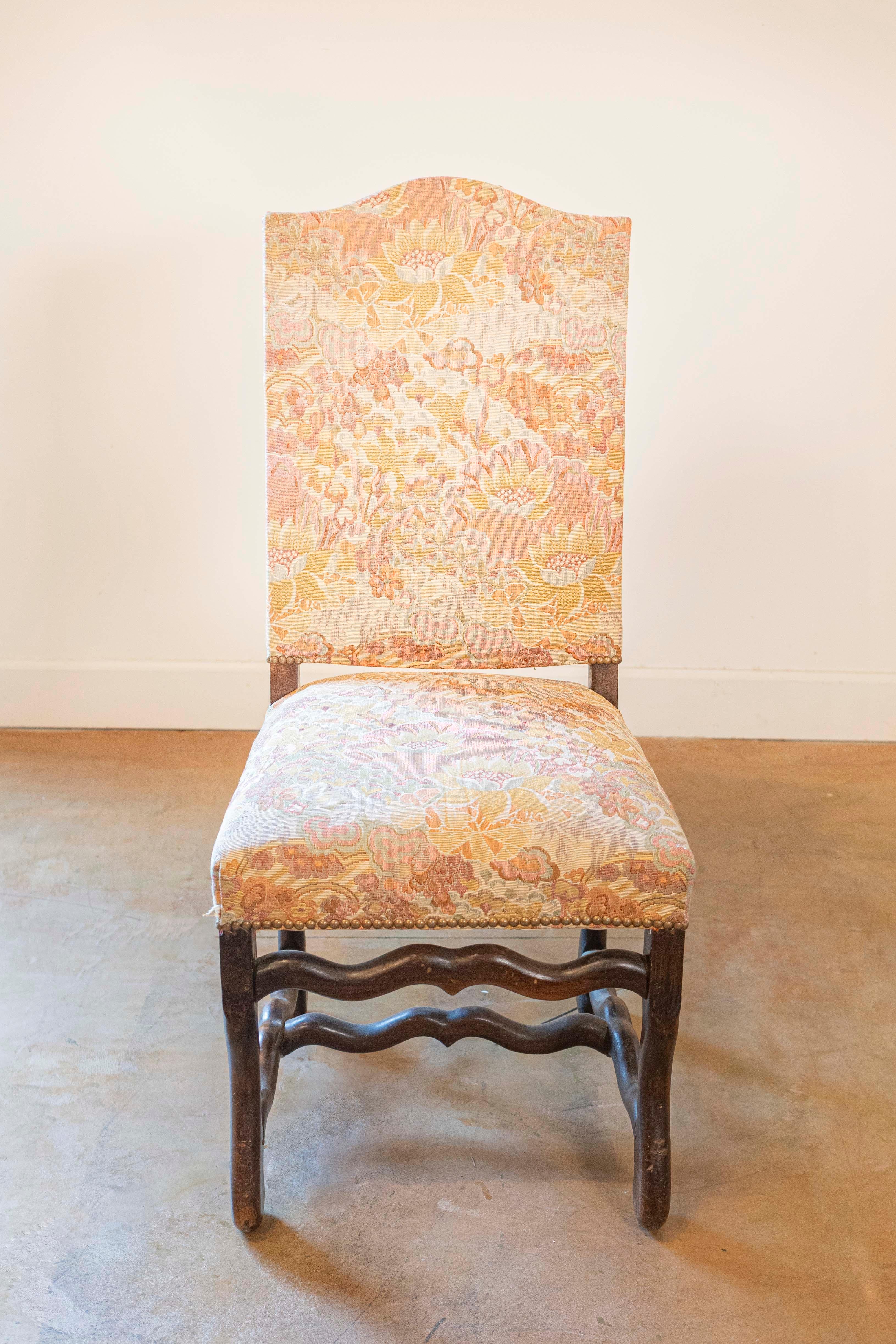 A set of six French Louis XIII style dining room side chairs from the 19th century, with os de mouton bases, slanted camelbacks, cross stretchers and used floral upholstery. Created in France during the 19th century, each of this set of side chairs