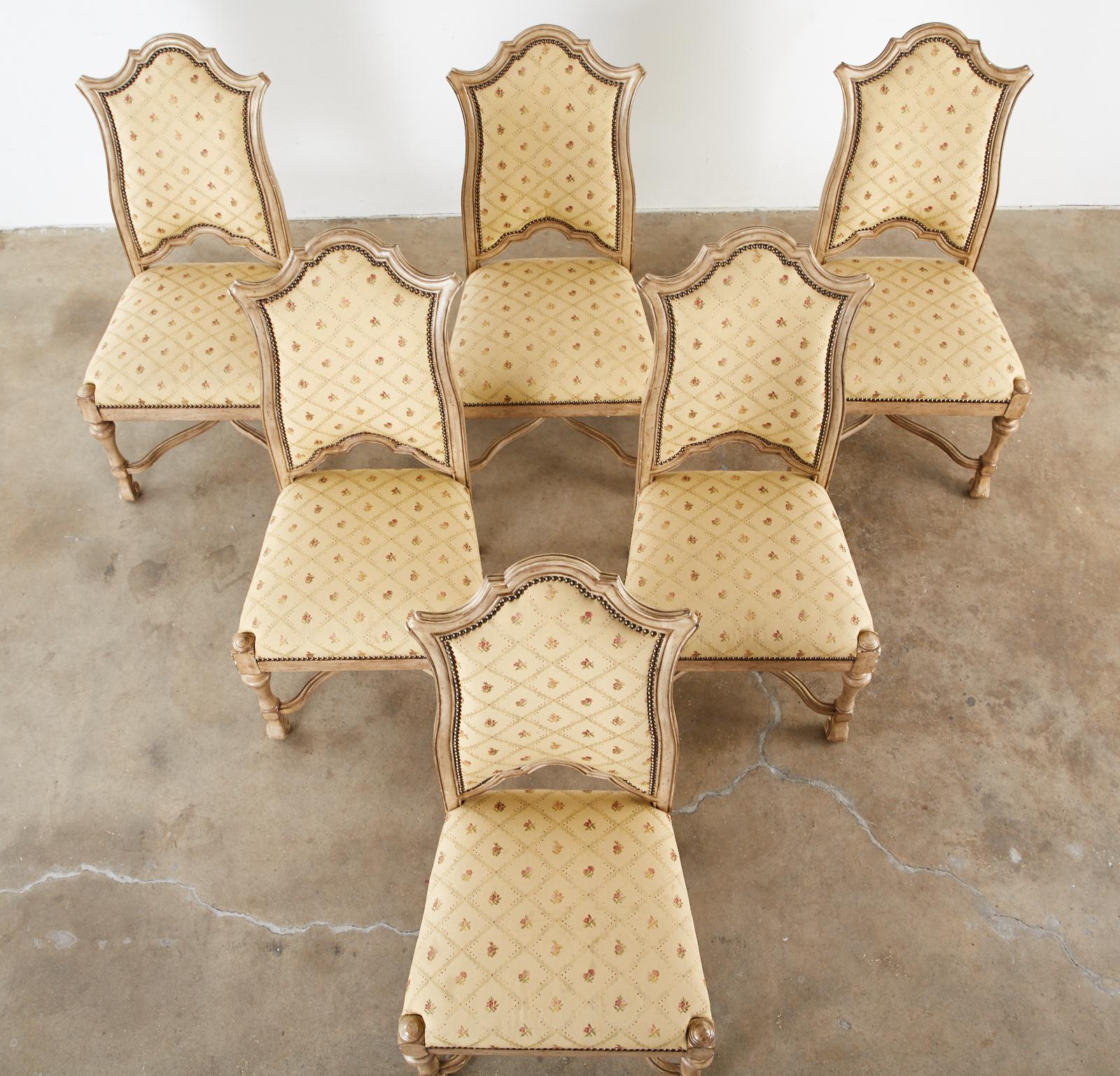 Distinctive set of six lacquered dining chairs by Ferguson Copeland. Made in the grand French Louis XIII style with peaked seat backs. The chairs have a vintage upholstery with brass tack nailhead borders. Supported by turned legs conjoined by x