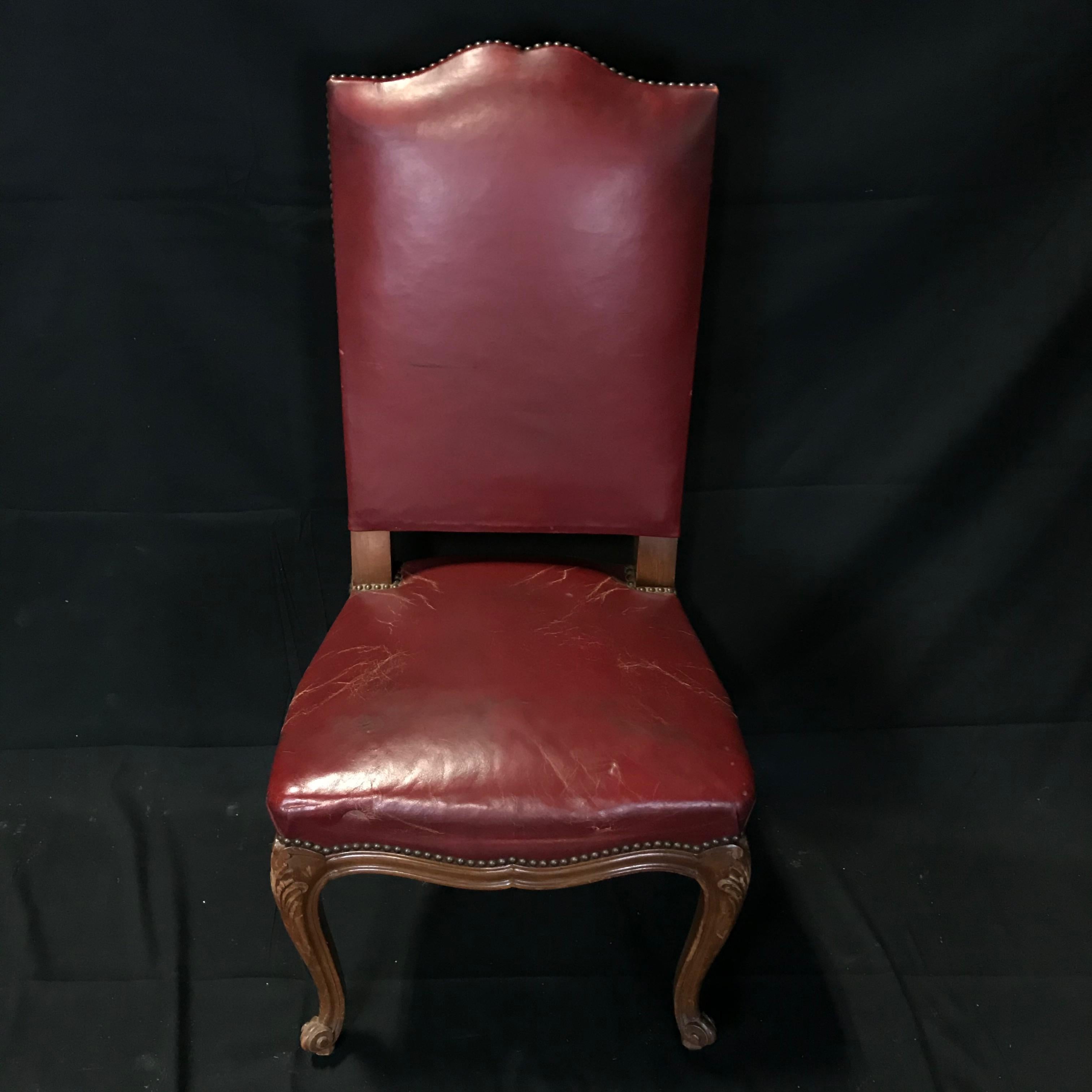 An exquisite set of six French Louis XV style 19th century walnut and dark red leather dining chairs having leather upholstered seats and backs, nailhead detailing and cabriole legs. Born during the 19th century, this set of French dining room side