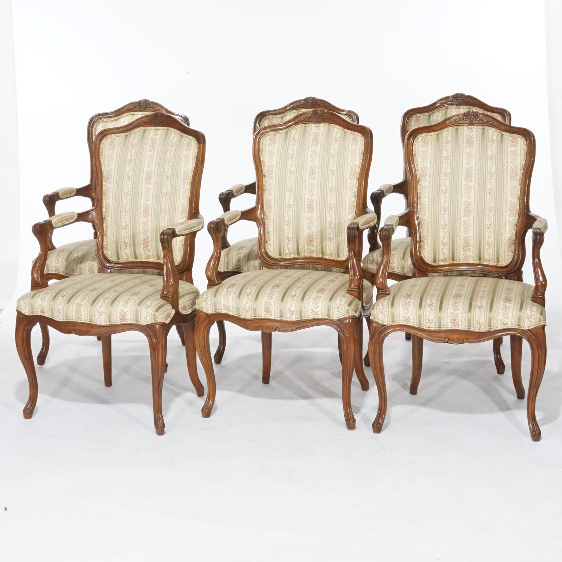 A set of six French Louis XV style armchairs offer upholstered backs and seats with walnut frame having carved crests, scroll form arms, and raised on cabriole legs, maker label as photographed, 20th century.

Measures- 40.25''H x 21.5''W x