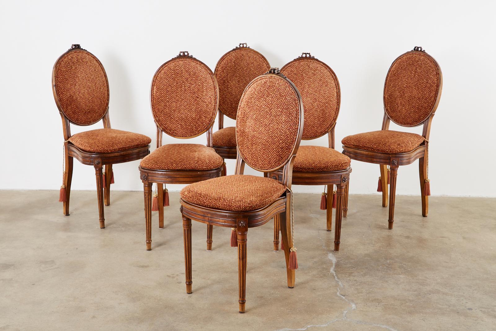 Extraordinary set of six 19th century French mahogany dining chairs featuring hand-caned seats. Made in the grand Louis XVI taste with neoclassical fluted column front legs. The rich mahogany frames have a round upholstered back with a chevron