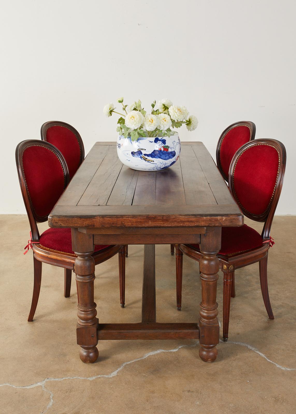 Dramatic set of six French mahogany caned dining chairs made in the Louis XVI taste. The chairs feature a rich velvet red upholstered back and loose seat cushion over cane. Classic French oval backs bordered with brass tack nail heads. The