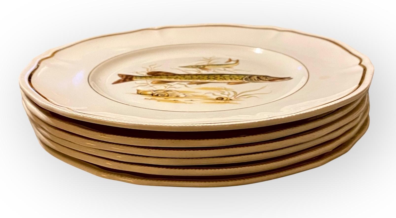 Un ensemble de six assiettes à poisson du milieu du siècle dernier par Longchamp, avec des formes et des bords joliment réticulés et dorés. Chacune représente une espèce de poisson différente.