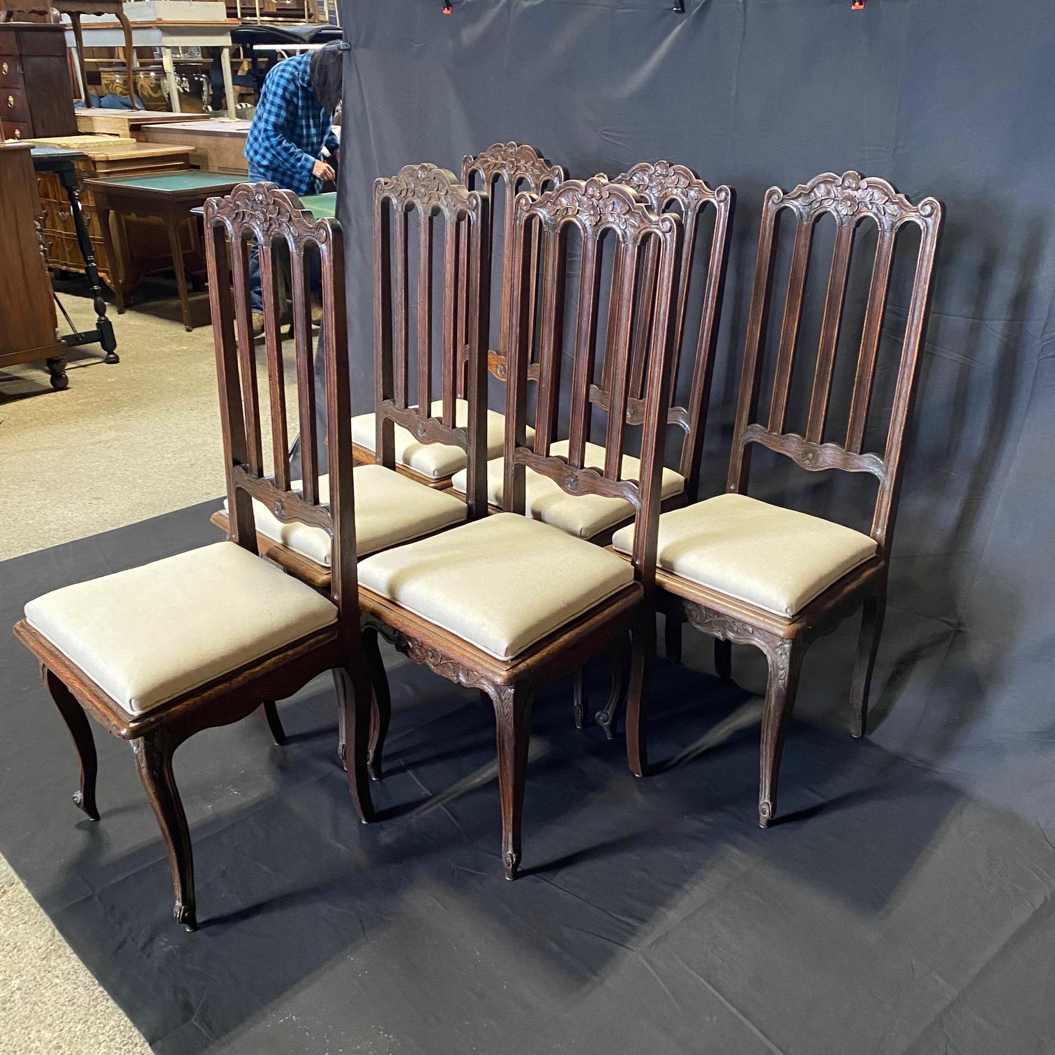 Exquisitely carved set of six oak dining chairs with beautifully decorated straight backs, cabriole legs with escargot snail feet and newly upholstered seats. Acanthus leaves, shells and floral twines are depicted on the chair aprons, feet and