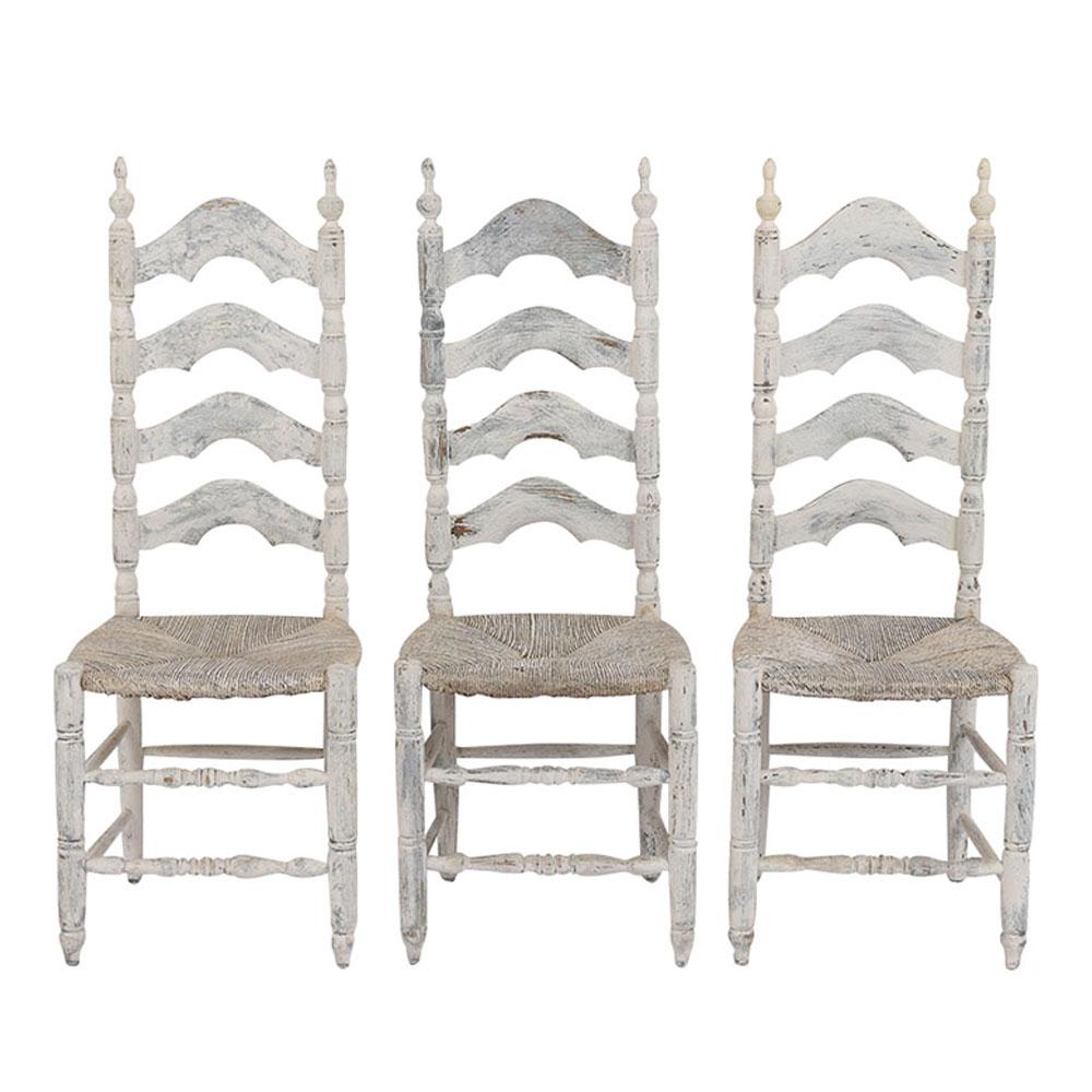 This set of six French Provincial dining chairs have been restored and are newly painted in off white color with a distressed finish. This set features a high ladder back design, stretched carved legs, and the original rush seats in a good