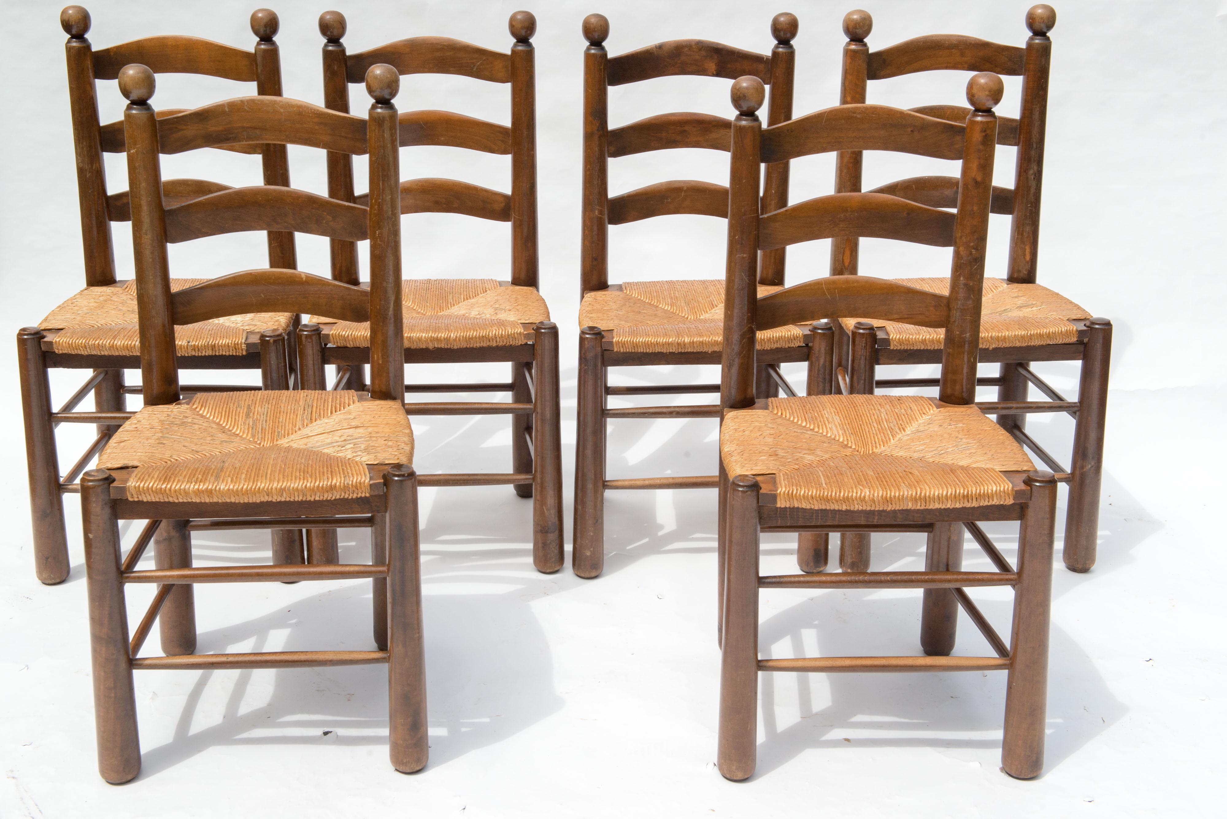 Set of six French rustic ladder back dining chairs with rush seats. Three curved slats on the backs. Double stretchers on all four sides. Turned ball finials. Excellent condition. We have another set of six chairs very similar to these.