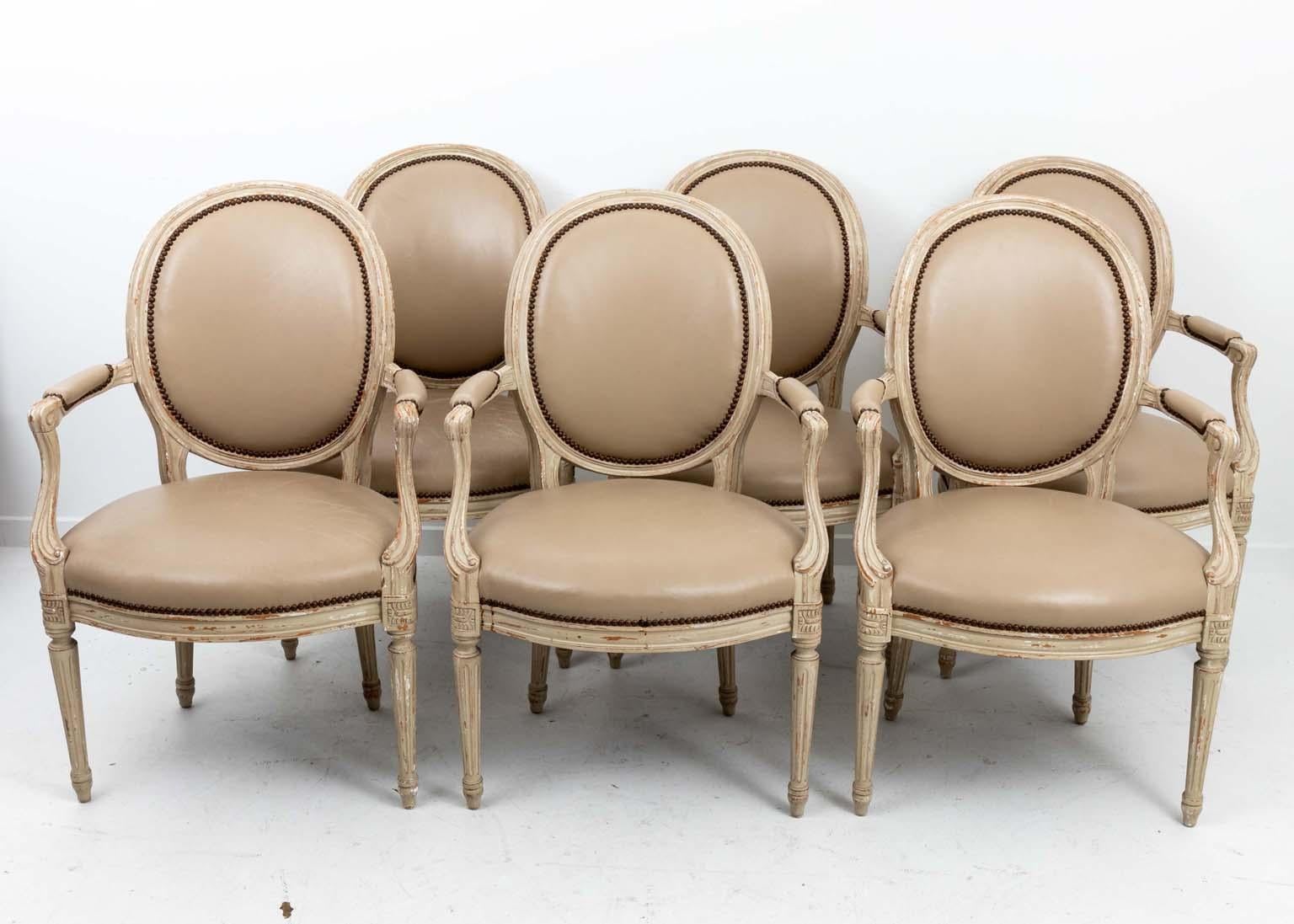 Set of six painted French style oval back chairs upholstered in leather with a check fabric on the back.
