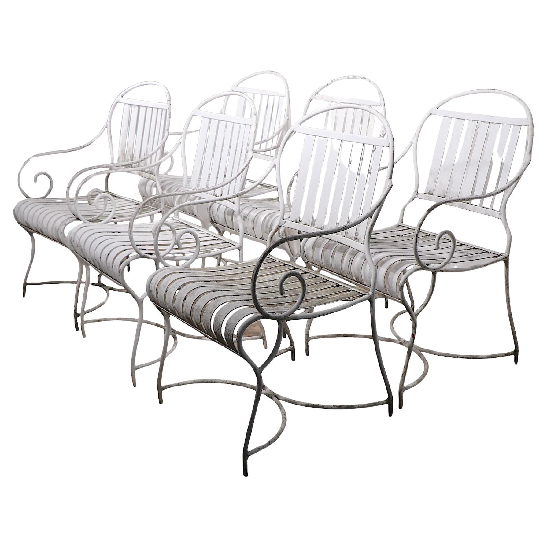 Set of six dining height arm chairs, constructed in aluminum, having curved tubular frames, with repeating seats and backs. Executed in the French style, made in the USA circa 1950/1970's. All six are structurally sound and sturdy, all show cosmetic