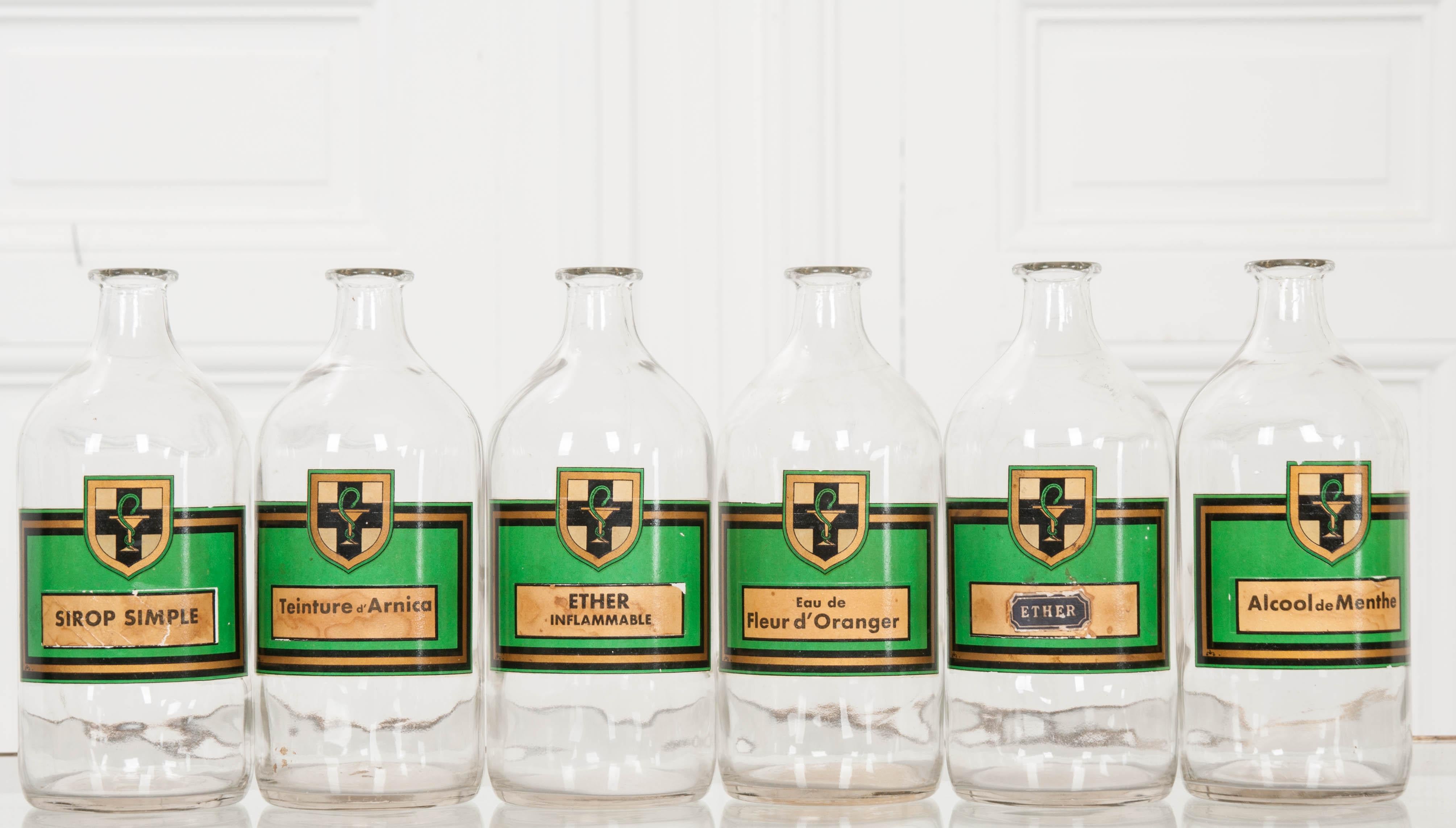 A fantastic set of six vintage apothecary bottles from a pharmacy in France. Wonderful green and gold labels are emblazoned, each with a bowl of Hygeia crest and the bottles’ contents labeled in French. Simple syrup, arnica tincture, ether (both