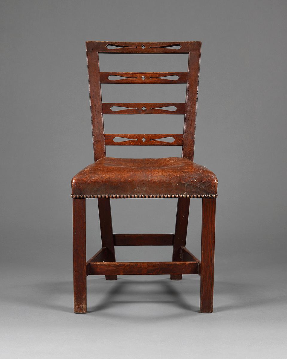 A set of six unusual George III Provincial oak dining chairs, with pierced ladder backs, close nailed leather upholstered stuff over seats, on moulded square legs united by stretchers.

English, circa 1800.