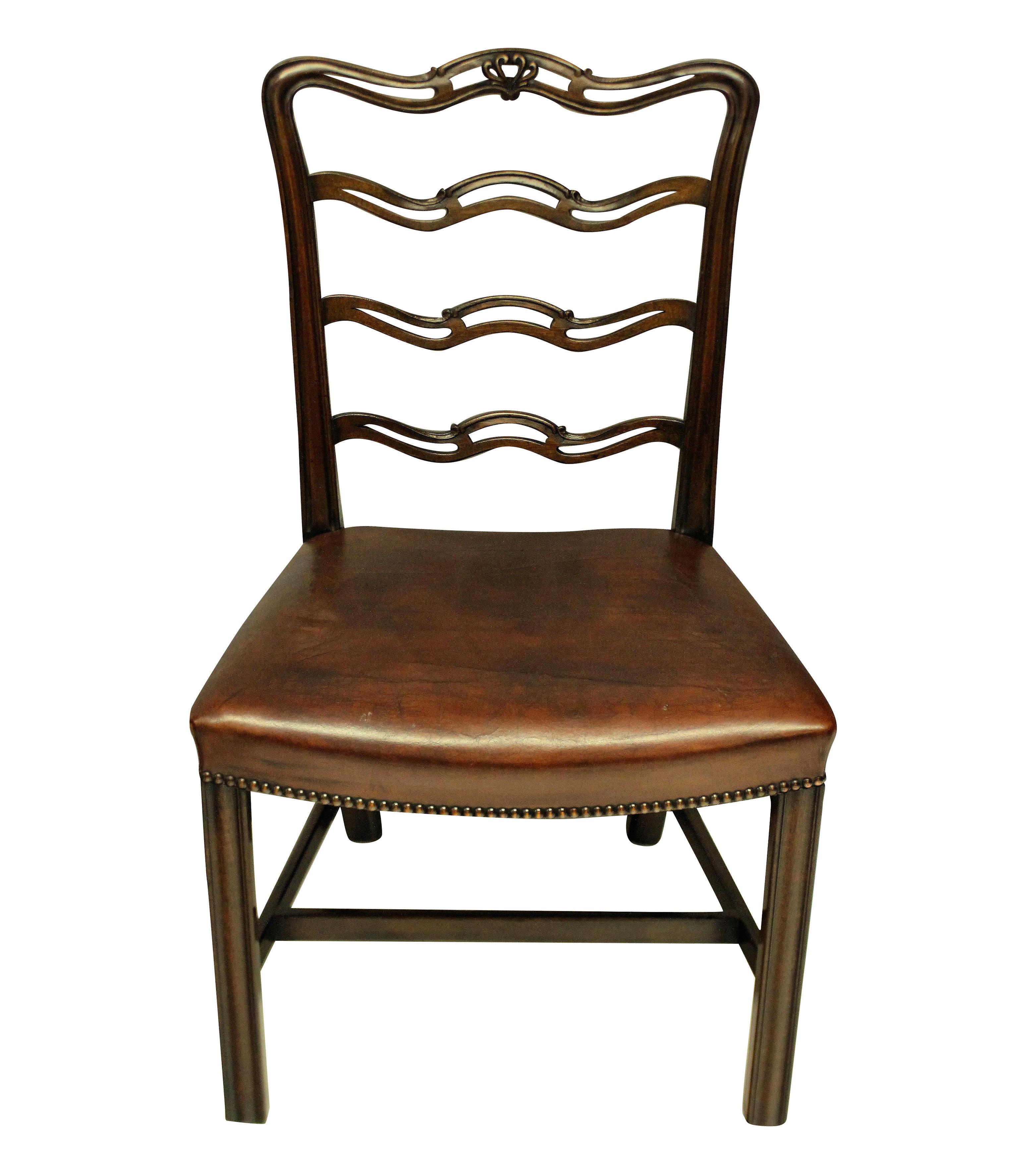 A set of six George III style mahogany ladder back dining chairs with the concave seats upholstered in leather with stud detail.