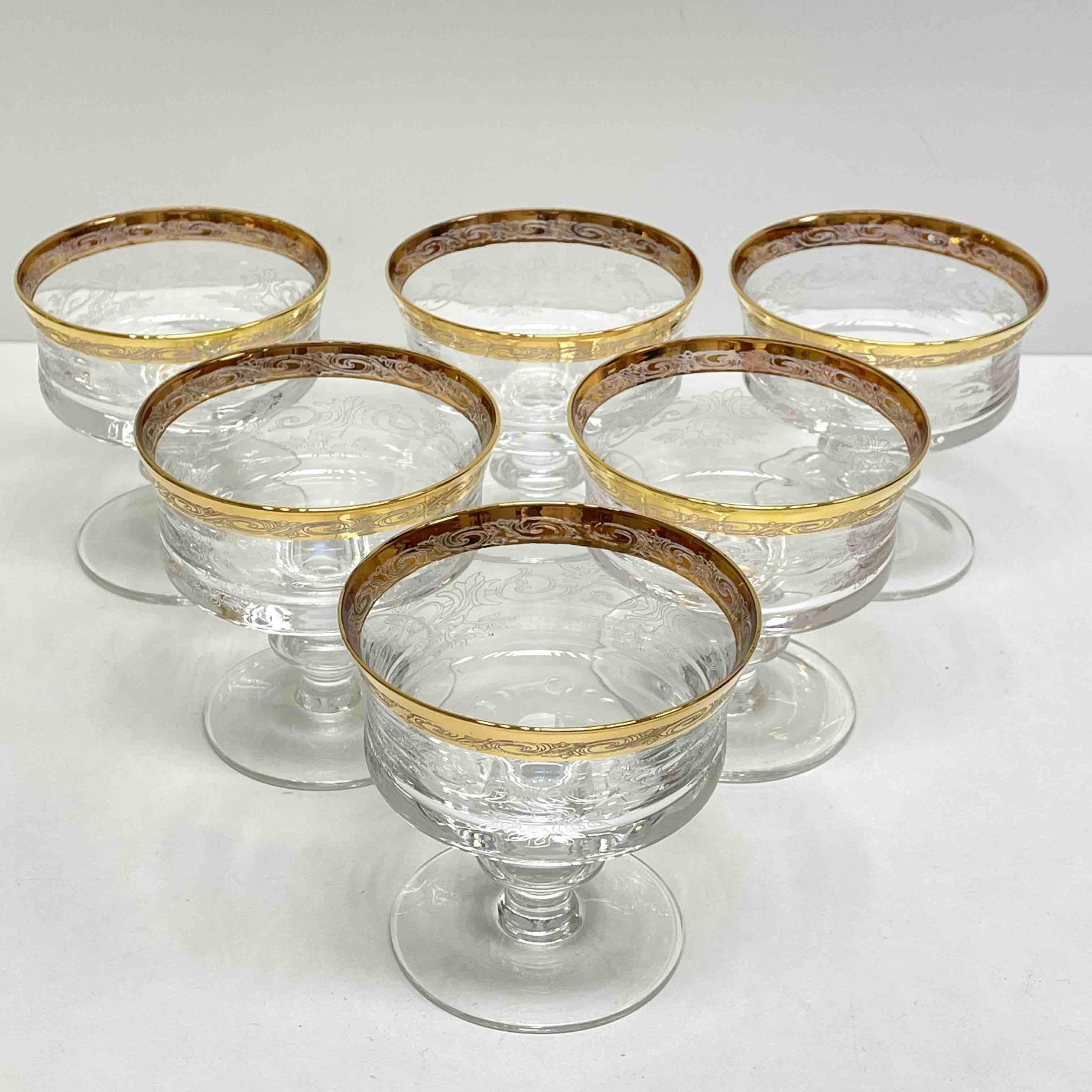 Beautiful hand blown champagne bowls, Six colorless thick Glasses, round stand, shaft with pointed nodus, bulbous bowl/body, stylized floral engraving and relief decoration, 24 karat gold-colored painted, gold rim. A nice addition to any table.