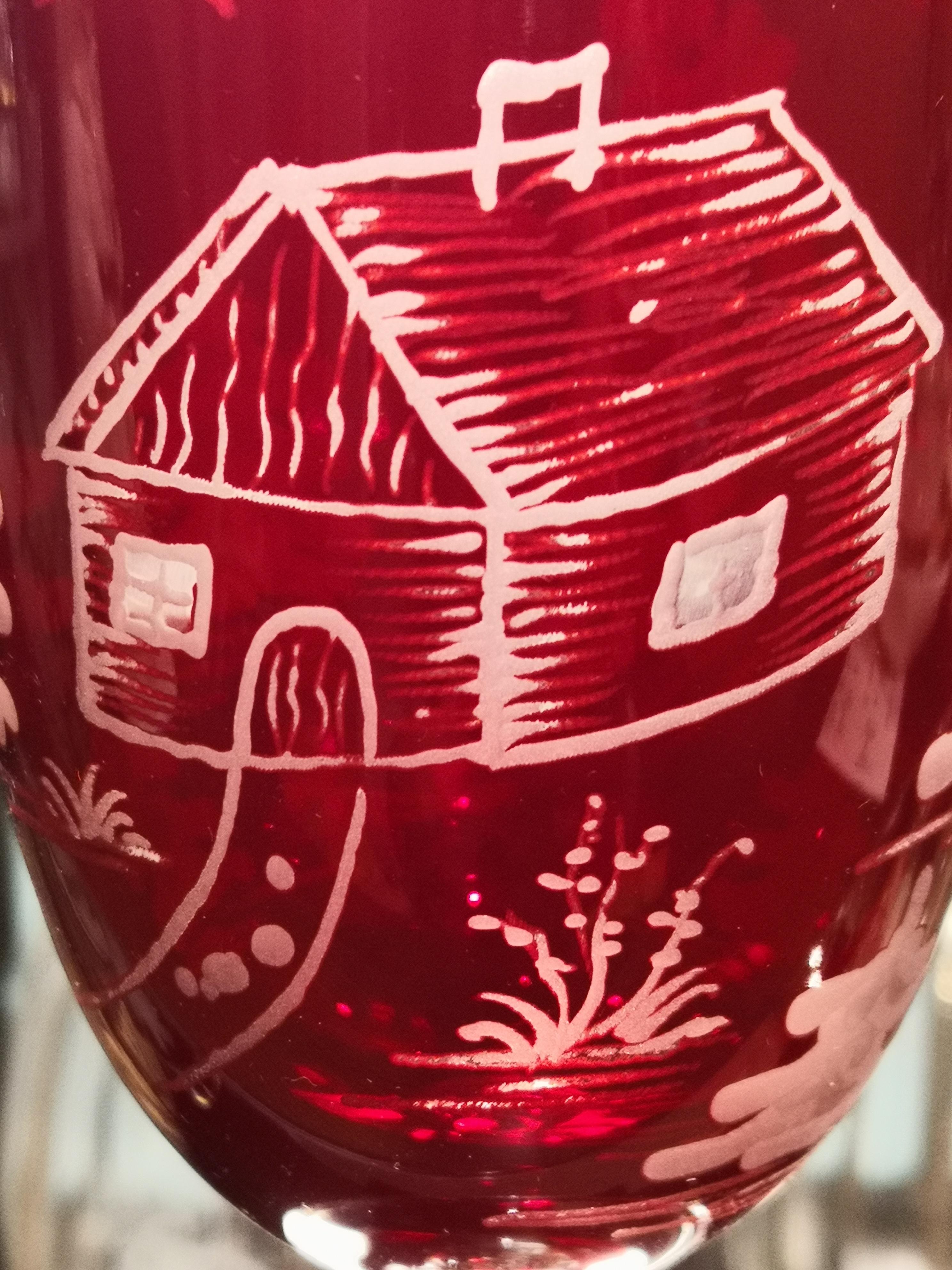 Set aus sechs mundgeblasenen Kristallgläsern in Rot mit einem mundgeblasenen Skifahrerdekor rundum. Das Dekor ist im Landhausstil gehalten und zeigt einen Skifahrerjungen, Bäume und Berge sowie eine Hütte auf dem Glas. Eine passende Kristallkaraffe