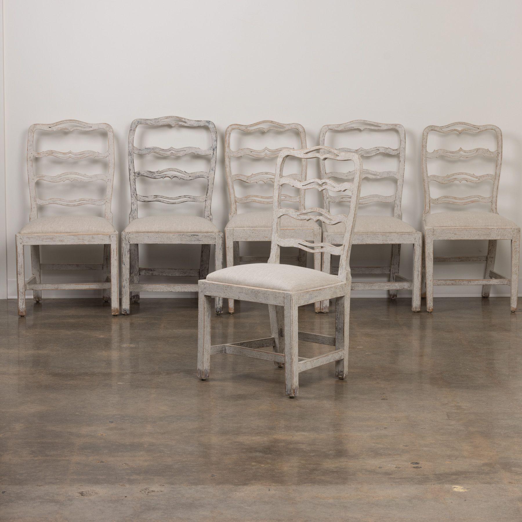 A matched set of 5 Swedish Gustavian period painted dining chairs from the 19th century, newly upholstered in linen with carved and pierced ladder backs and slip seats. This is an exquisite set of chairs.
The Gustavian style, named after King Gustav