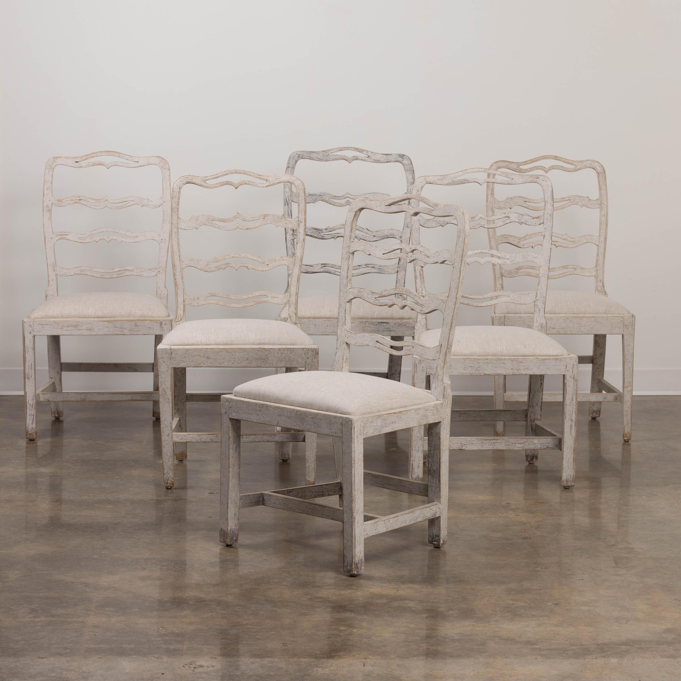 Ein zusammengehöriger Satz von 5 schwedischen, bemalten Esszimmerstühlen aus dem 19. Jahrhundert, neu mit Leinen bezogen, mit geschnitzten und durchbrochenen Leiterlehnen und Schlupfsitzen. Dies ist ein exquisiter Satz von Stühlen.
Der