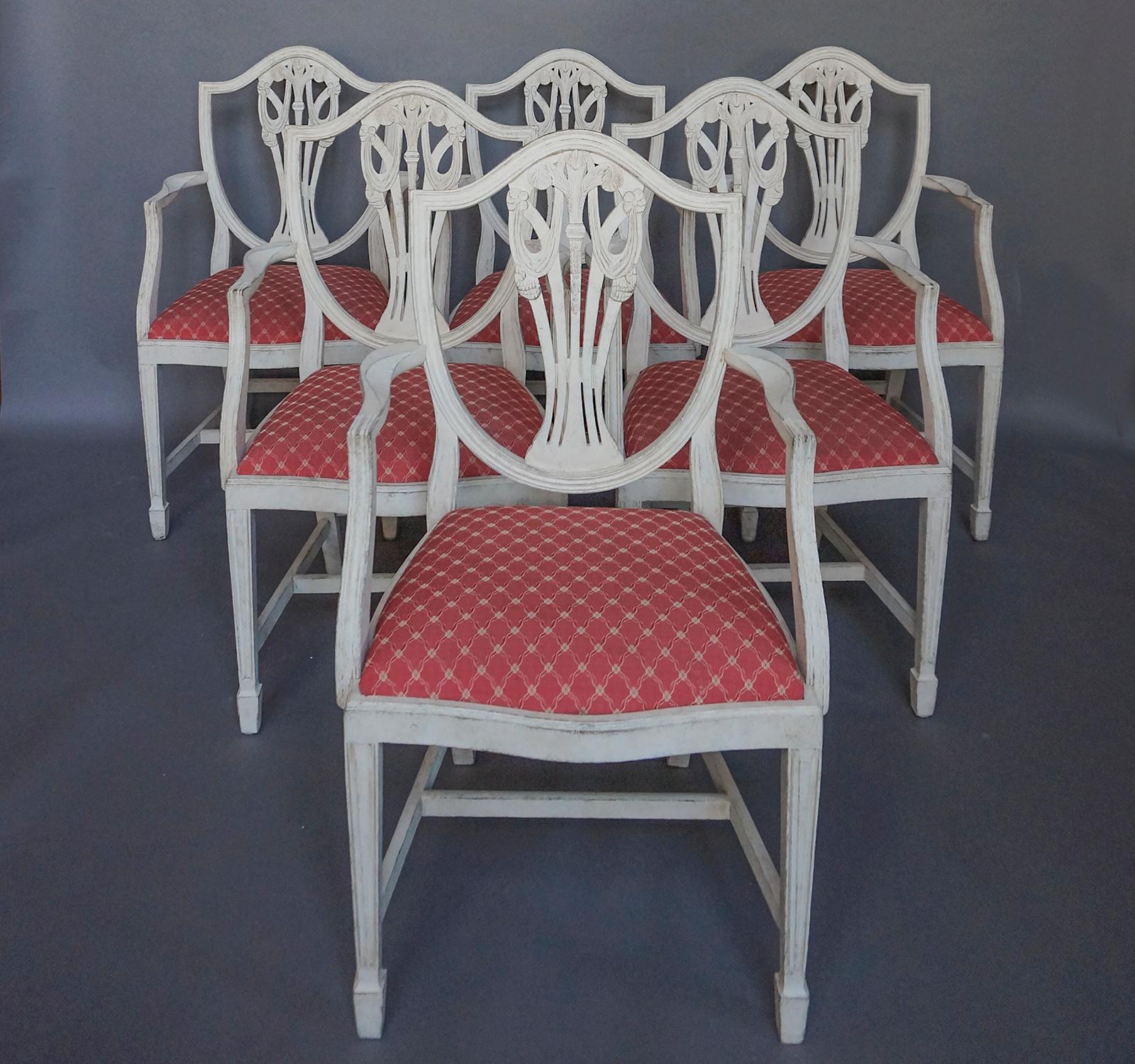 Set of 6 armchairs in the Gustavian style, Sweden, circa 1910. Beautiful carving with feathers, flowers and swags on the shield-shaped backs. Reeded and tapering front legs ending in spade feet. Slip seats.