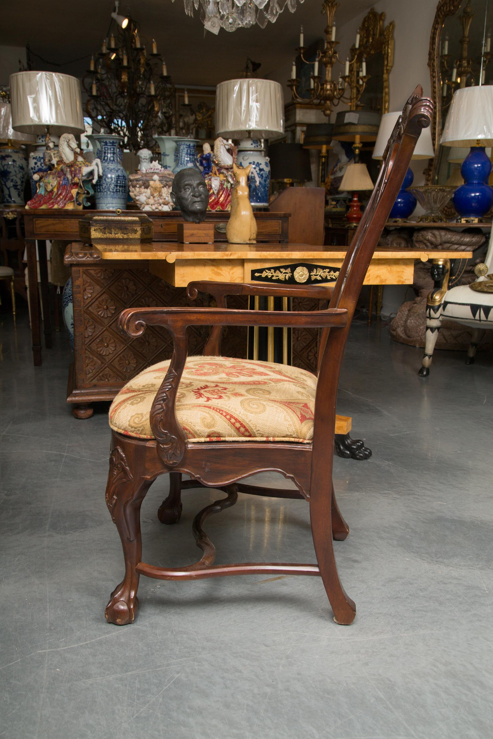This is an elegant set of six mahogany Irish Chippendale dining chairs. The set is comprised of two arm and four side chairs with ornately carved top rail, apron and knees supported by cabriole legs terminating in hoof feet and joined by a scrolling