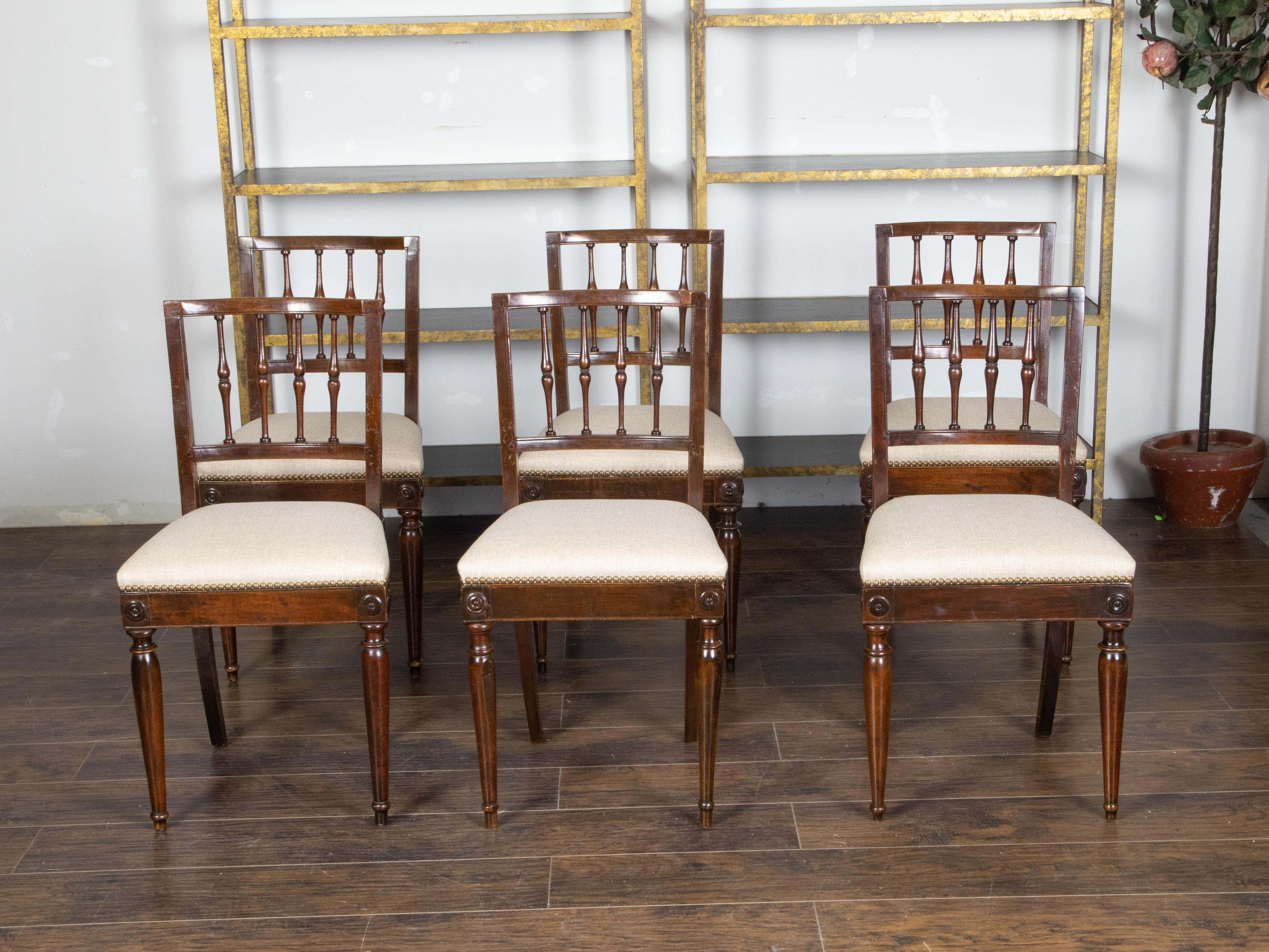 Un set di sei sedie da sala da pranzo in noce italiano degli inizi del XIX secolo, con schienali a fuso, medaglioni intagliati e tappezzeria nuova. Creata in Italia nei primi anni del XIX secolo, questa serie di poltroncine in noce presenta uno