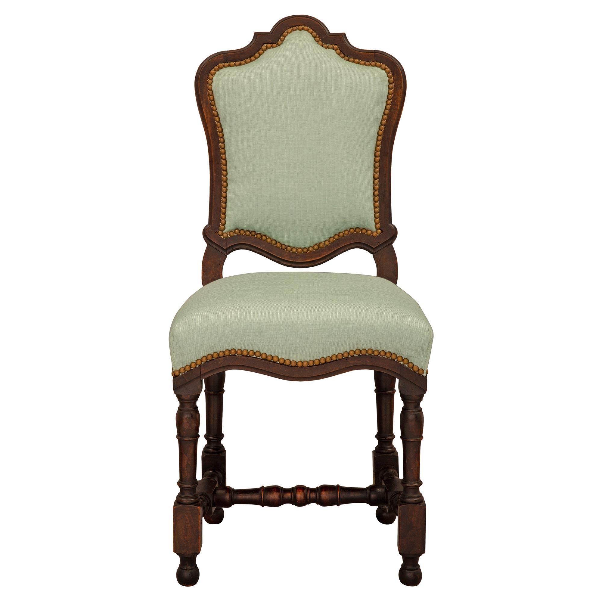 A handsome and complete set of six Italian 18th century Louis XIV period walnut dining chairs. Each chair is raised by elegant ball feet below block reserves and lovely turned legs each connected by a finely mottled stretcher. The seat displays a