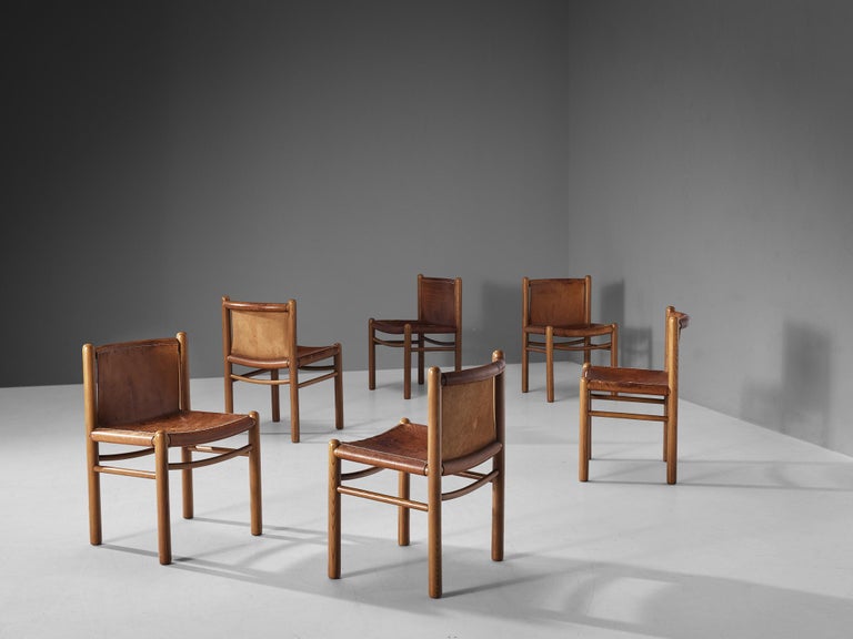 Dining chairs, elm, saddle leather, Italy, 1960s. 

Elegant set of six Italian dining chairs. The design of these chairs shows organic lines beautifully expressed by the used materials. Executed in solid elm wood, the frame features rounded forms