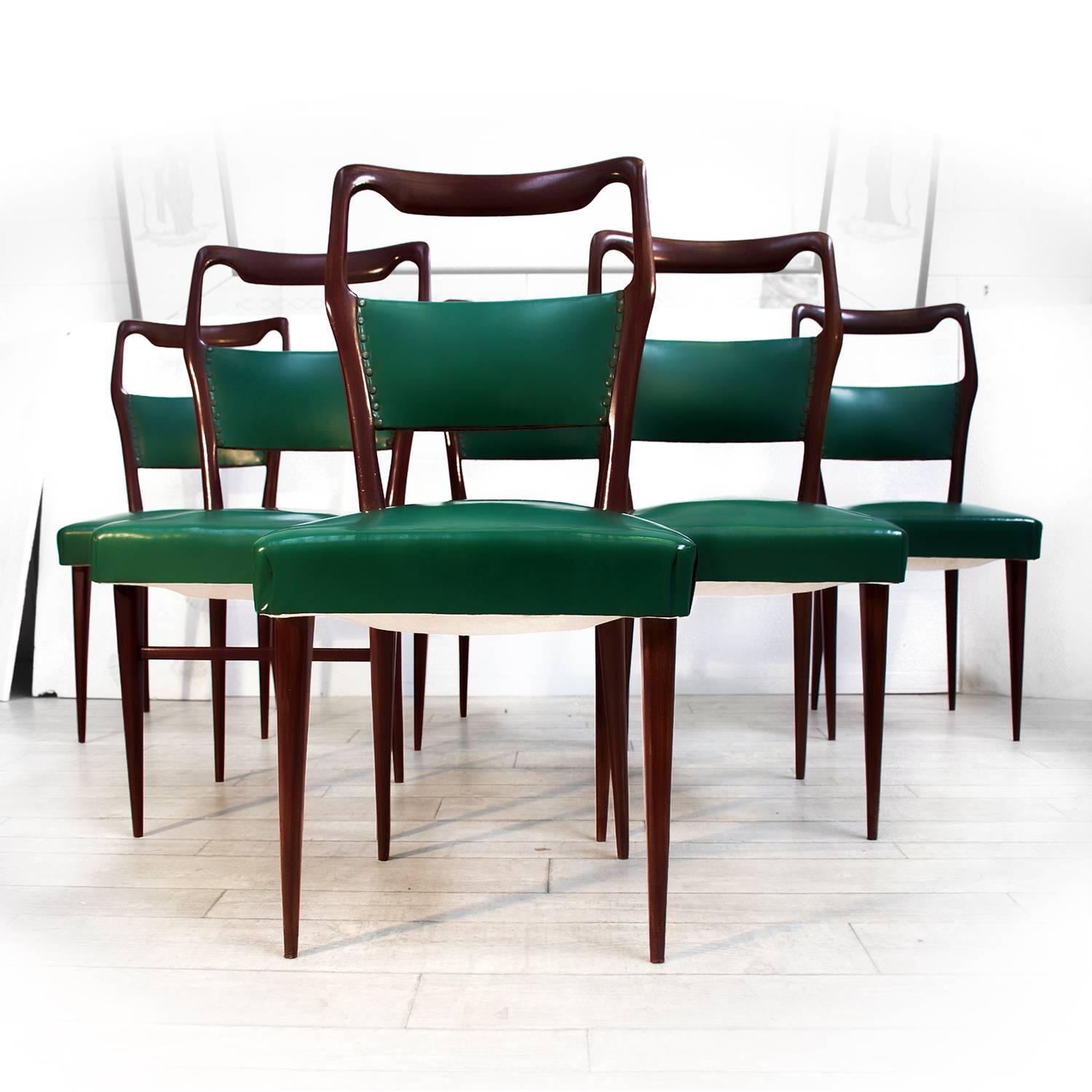 Elegant lines and solid mahogany structures for this set of six dining chairs designed by Vittorio Dassi in the 1950s.
The wood surfaces, as well the upholstery green leatherette, springs and padding are in good conditions of the period, with minor